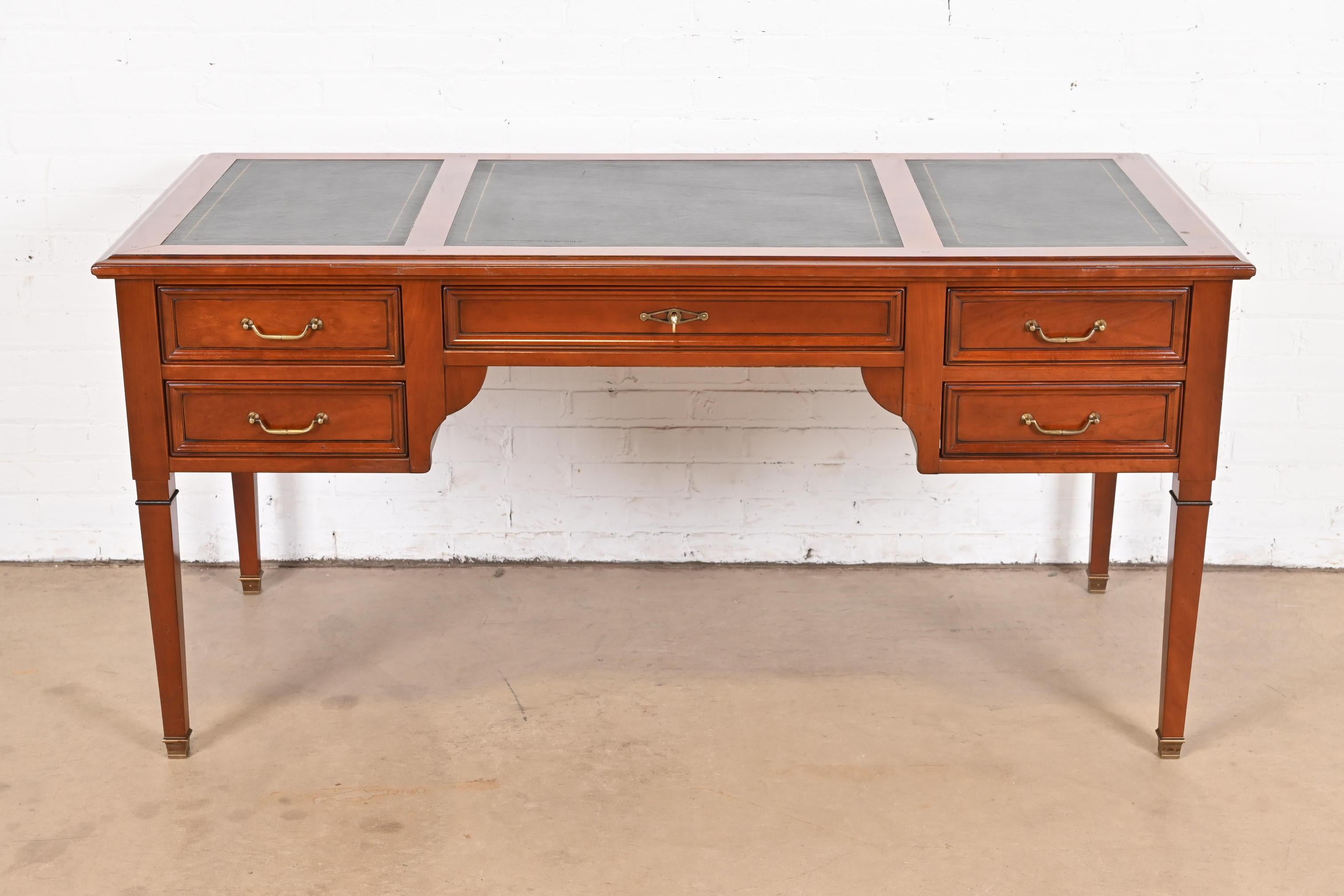 An exceptional French Regency Louis XVI style bureau plat desk or writing desk

By Grange

France, Circa Late 20th Century

Solid cherry wood, with brass hardware and embossed leather top.

Measures: 63