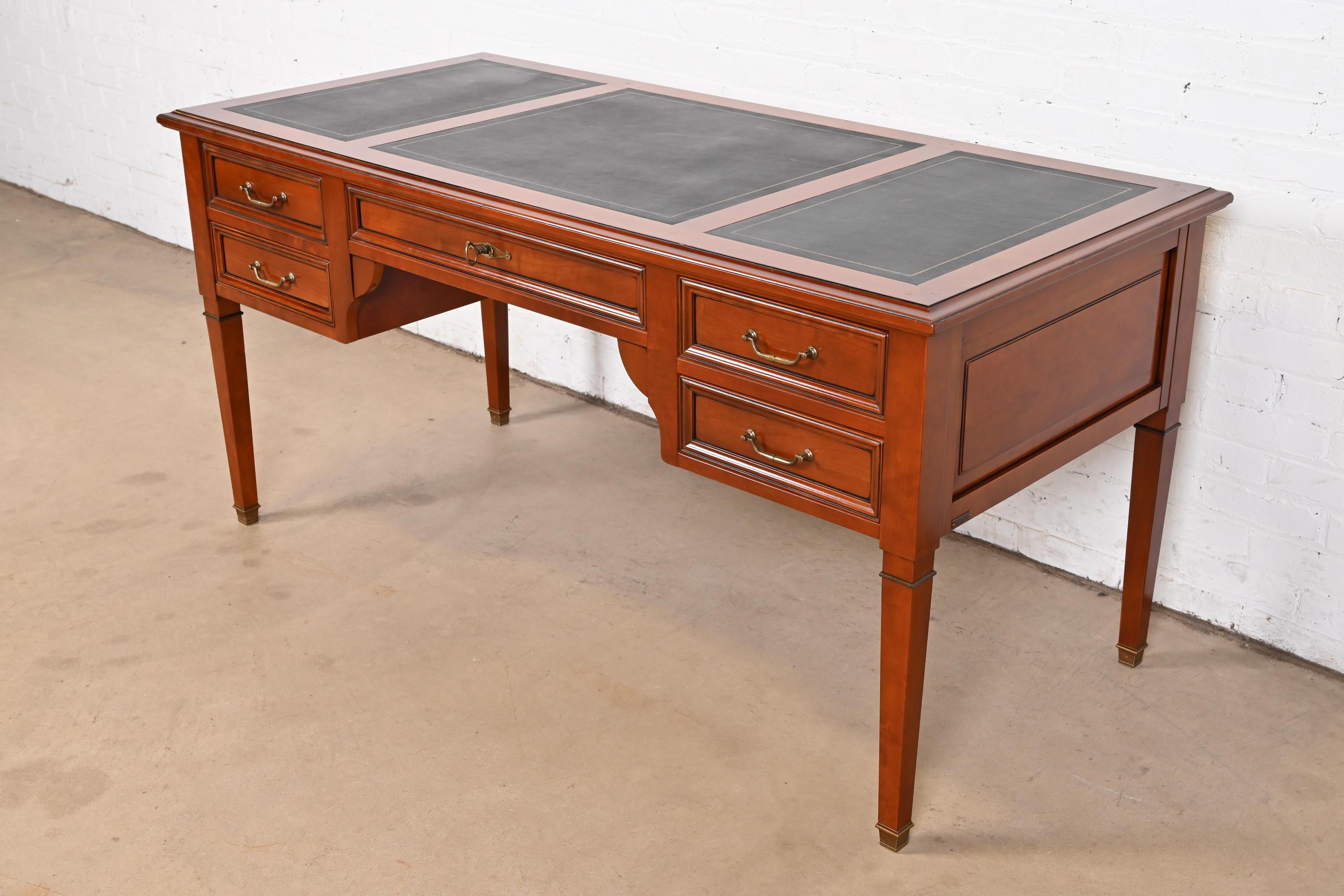 An exceptional French Regency Louis XVI style bureau plat desk or writing desk

By Grange

France, Circa Late 20th Century

Solid cherry wood, with brass hardware and embossed leather top.

Measures: 63