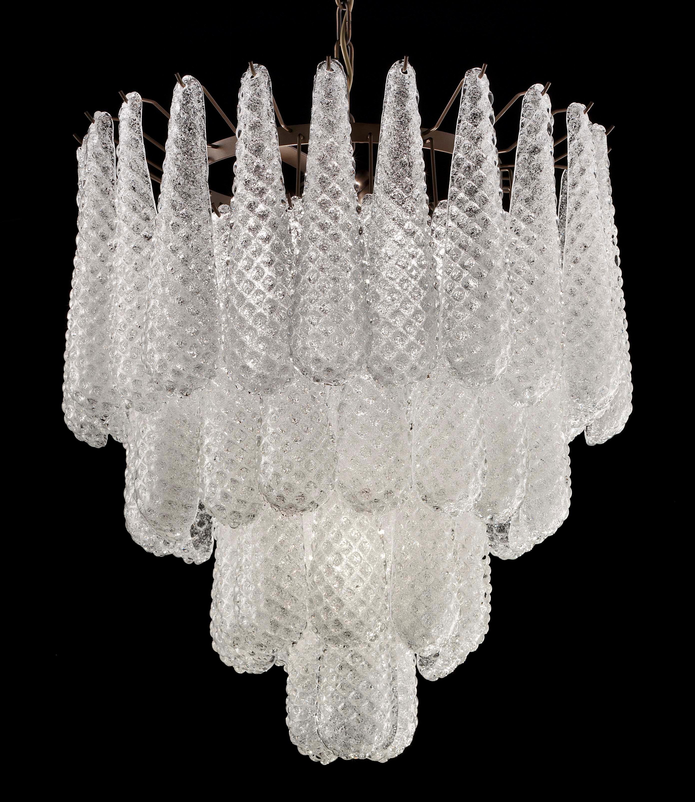 Lampadario italiano con gocce in vetro di Murano trasparente a lacrime soffiate a mano con la tecnica Graniglia per ottenere un effetto granulare, montato su una struttura in metallo con finitura bronzata da Fabio Ltd / Made in Italy
5 luci / 4 di