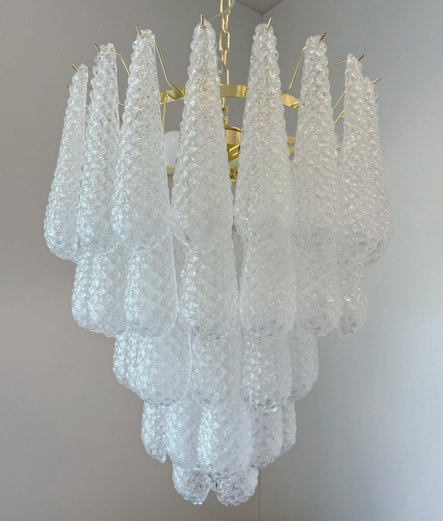 Lámpara de araña italiana con gotas de cristal transparente de Murano soplado a mano con la técnica Graniglia para producir un efecto de textura granular, montada en una estructura de metal dorado por Fabio Ltd / Made in Italy
Medidas: diámetro 25,5