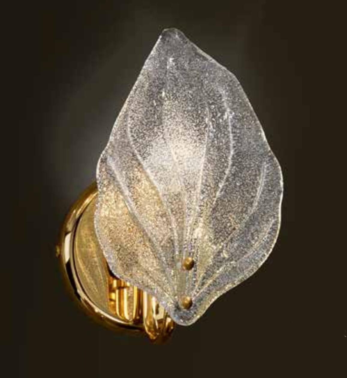 Aplique italiano con una gran hoja de cristal de Murano soplada a mano con la técnica Graniglia para producir un efecto de textura granular, apoyado en un marco de metal acabado en oro / Made in Italy 
1 luz / tipo E12 o E14 / máx. 40W  
Medidas: