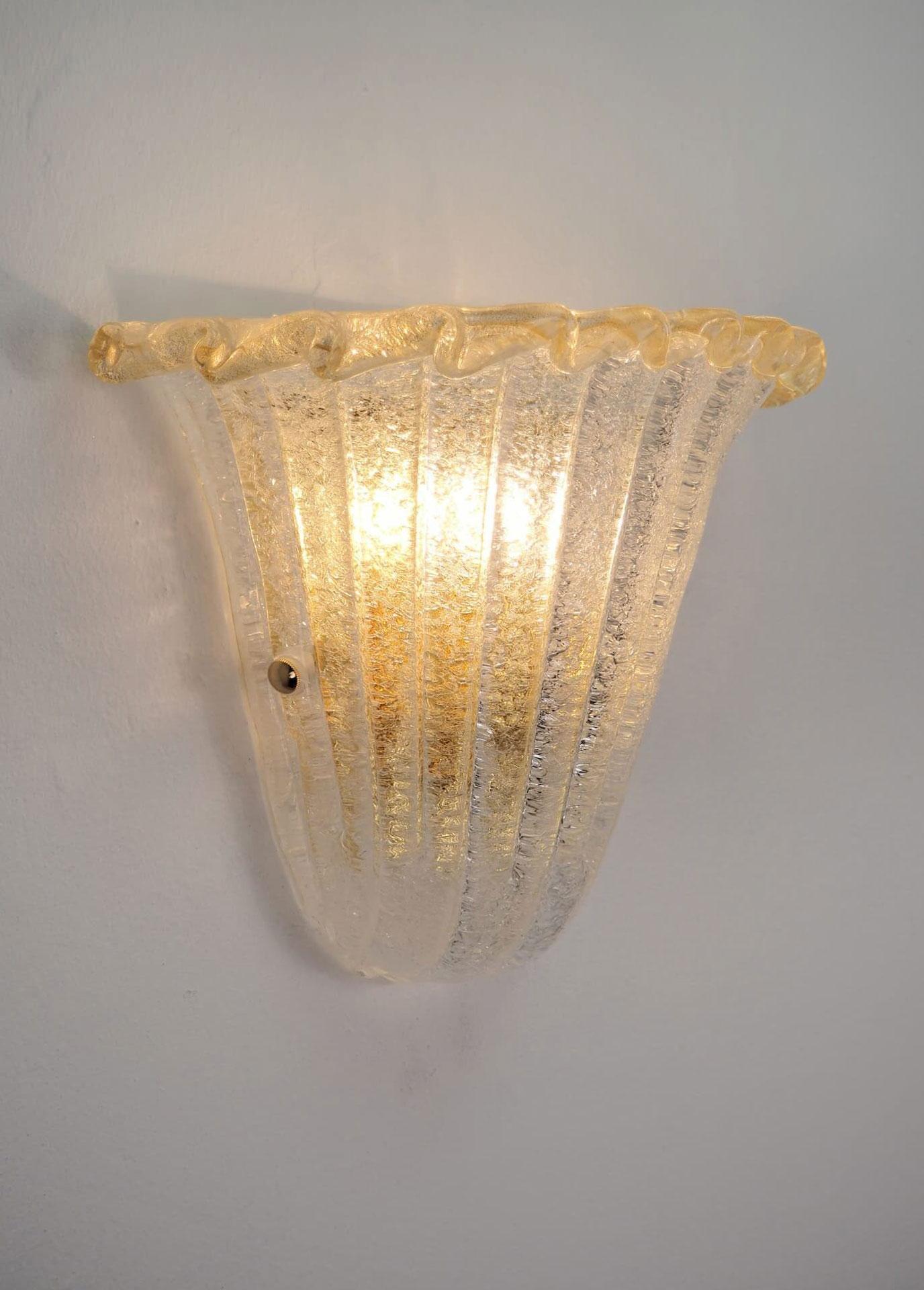 Italian wall light with a Murano glass shield hand blown in Graniglia technique to produce granular textured effect with gold flecks infused in the rim, mounted on gold plated finish frame / Made in Italy
Measures: Height 10 inches, width 12 inches,