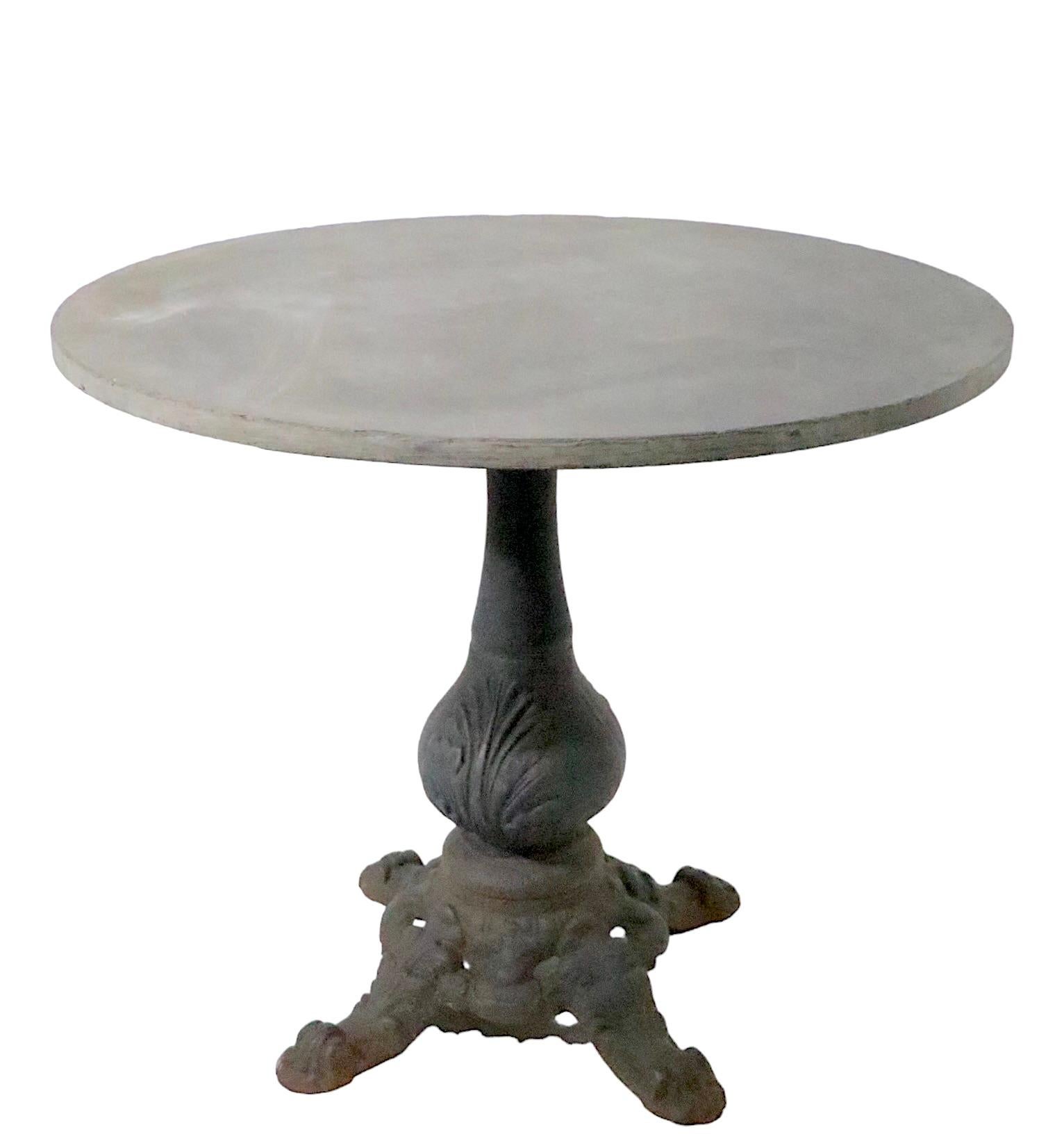 Nice cast iron base, slate, or granite top cafe, bistro, garden, patio table in the Victorian, French Provincial style, probably early 20th C production. The base is substantial, and heavy, making the table very sturdy and stable when the round