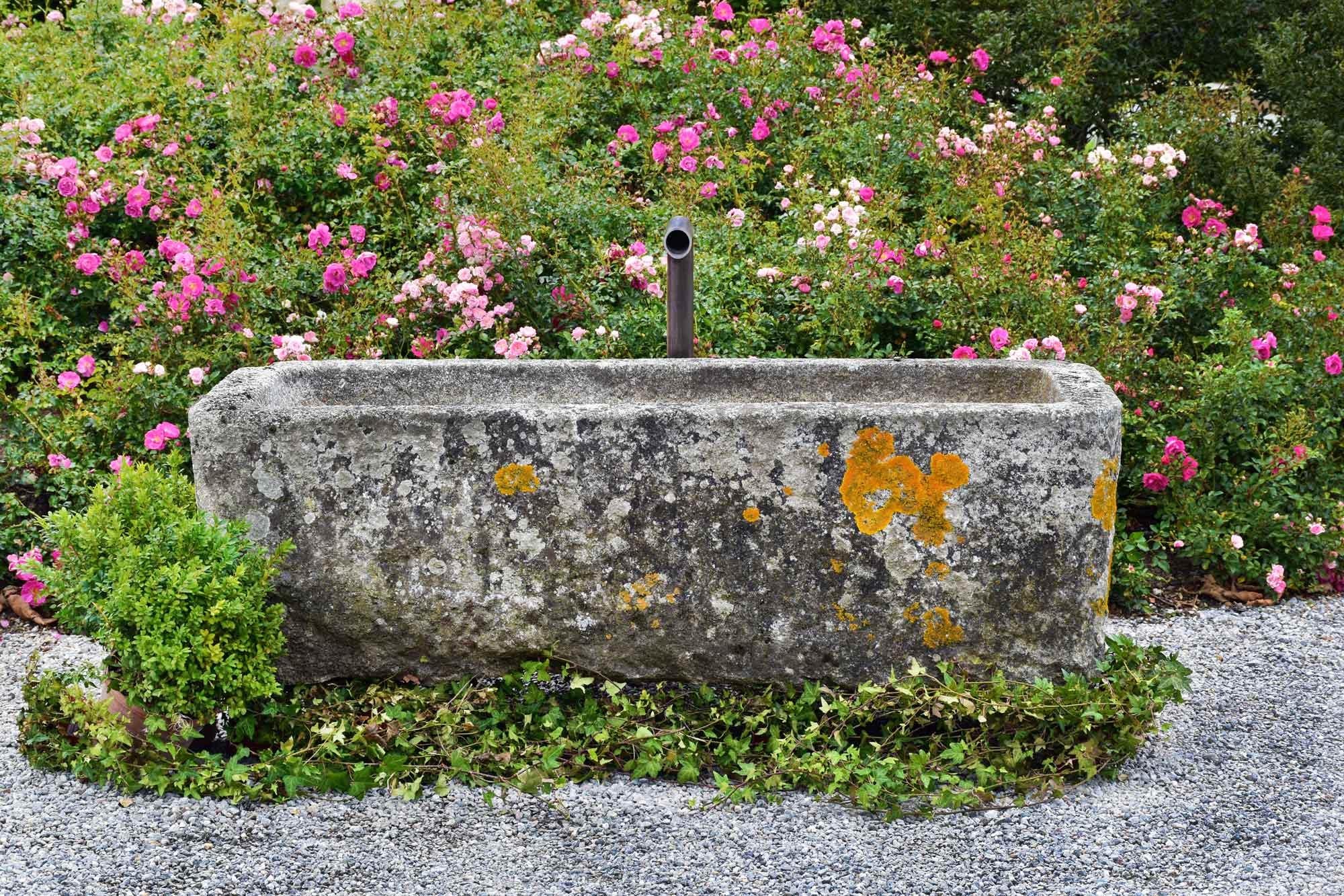 This small granite trough has a nice patina and a curved line. The shape is not perfectly straight but this makes it even more special. The trough has a nice size and it looks perfect in a garden full of flowers.