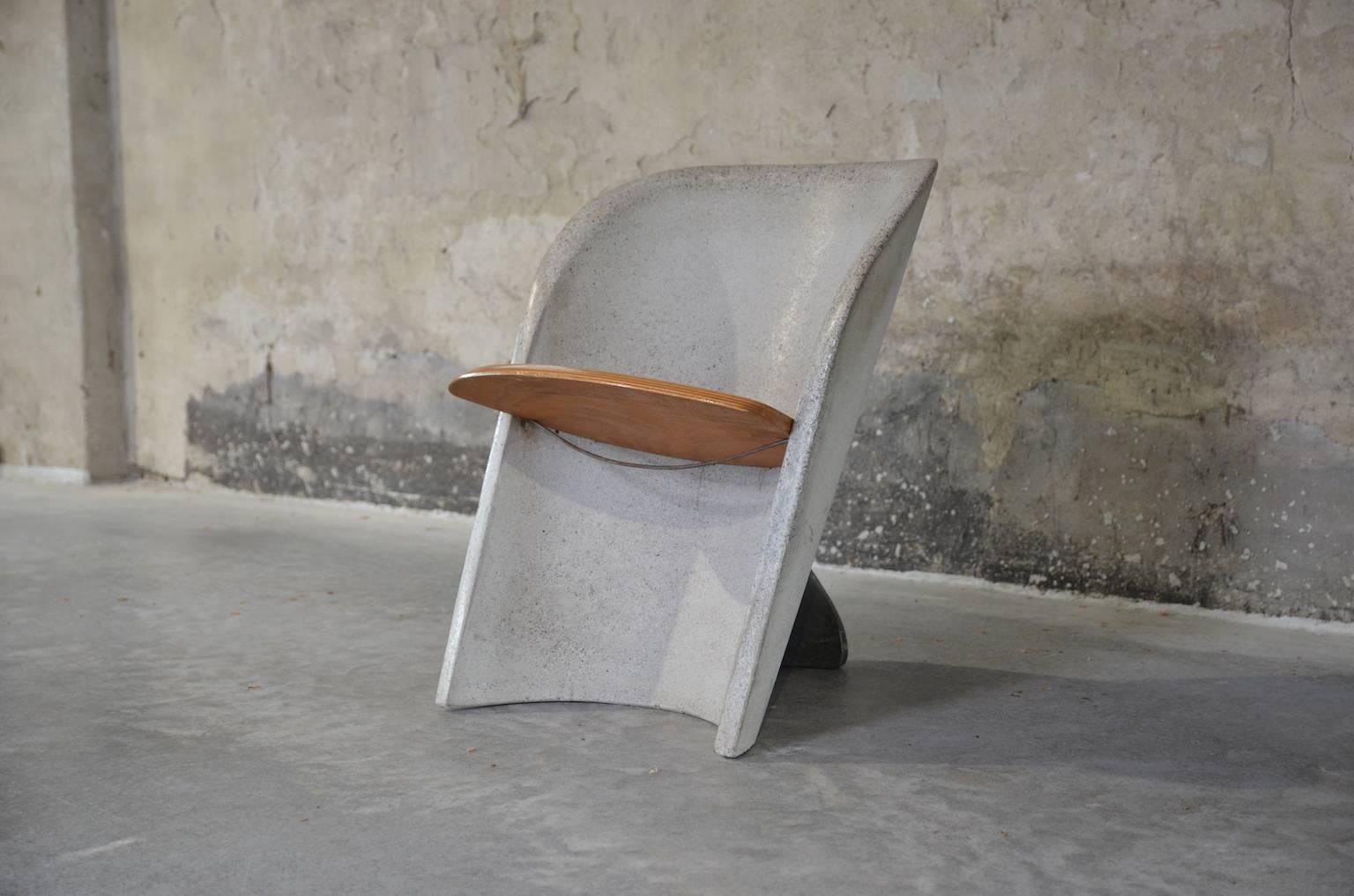 Remarkable granito chair in a semi-circular form. The grey chair remains its balance by a black fin in the back of the chair. The (removable) seat is made of wood.