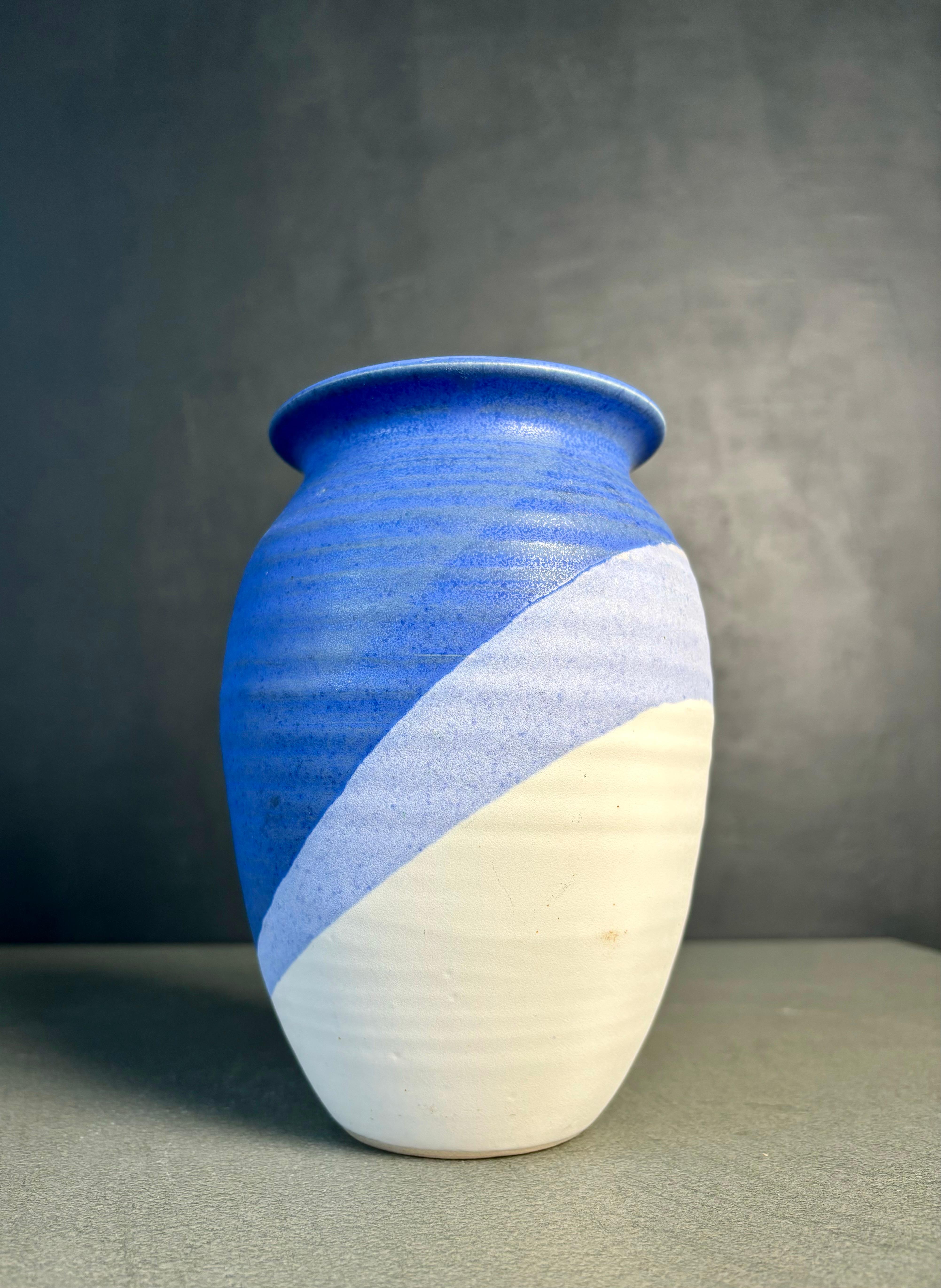 Vaso in ceramica danese modernista con smalto blu opaco su smalto lilla e bianco a strisce asimmetriche che accentuano la forma organicamente morbida. Realizzato a mano in Danimarca da KN Keramik negli anni '80. Firmato sotto la base. Bellissime