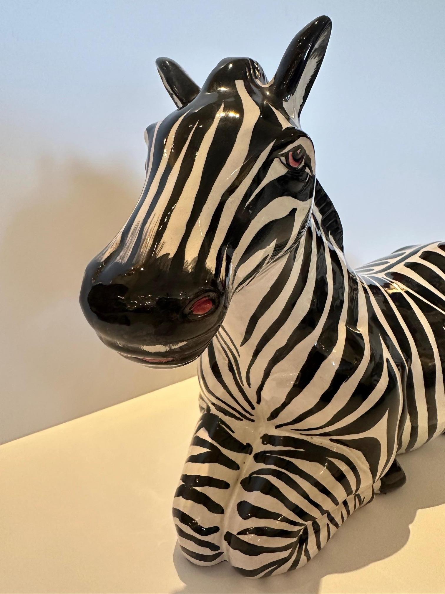 Scultura in terracotta smaltata di una zebra supina proveniente dall'Italia.