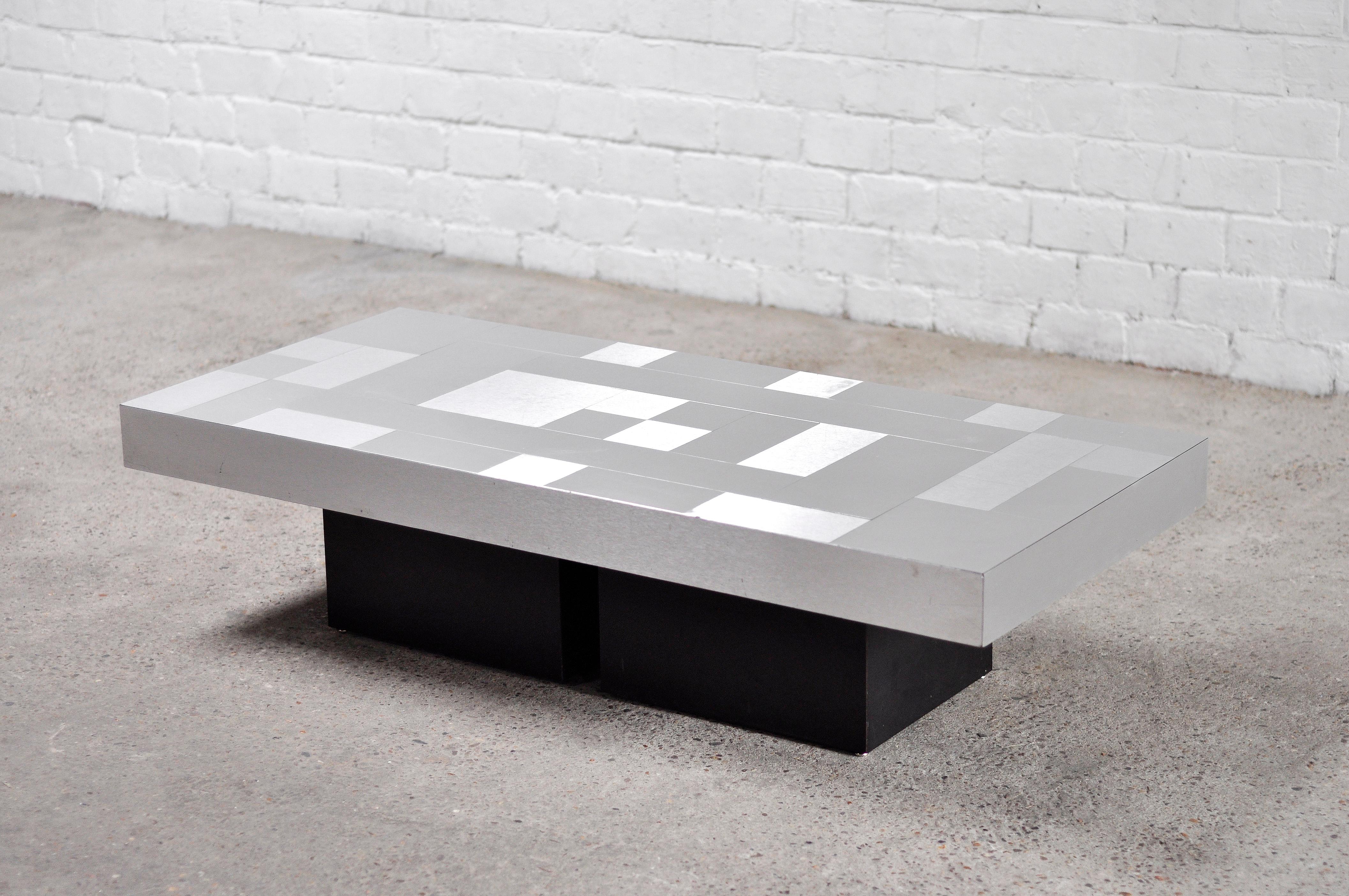 Brushed aluminum coffee table featuring a graphical mosaic or checkerboard style tablet. The central base is made of qualitative black laminated wood.

In fair condition for the age. There are signs of wear to the top in the form of