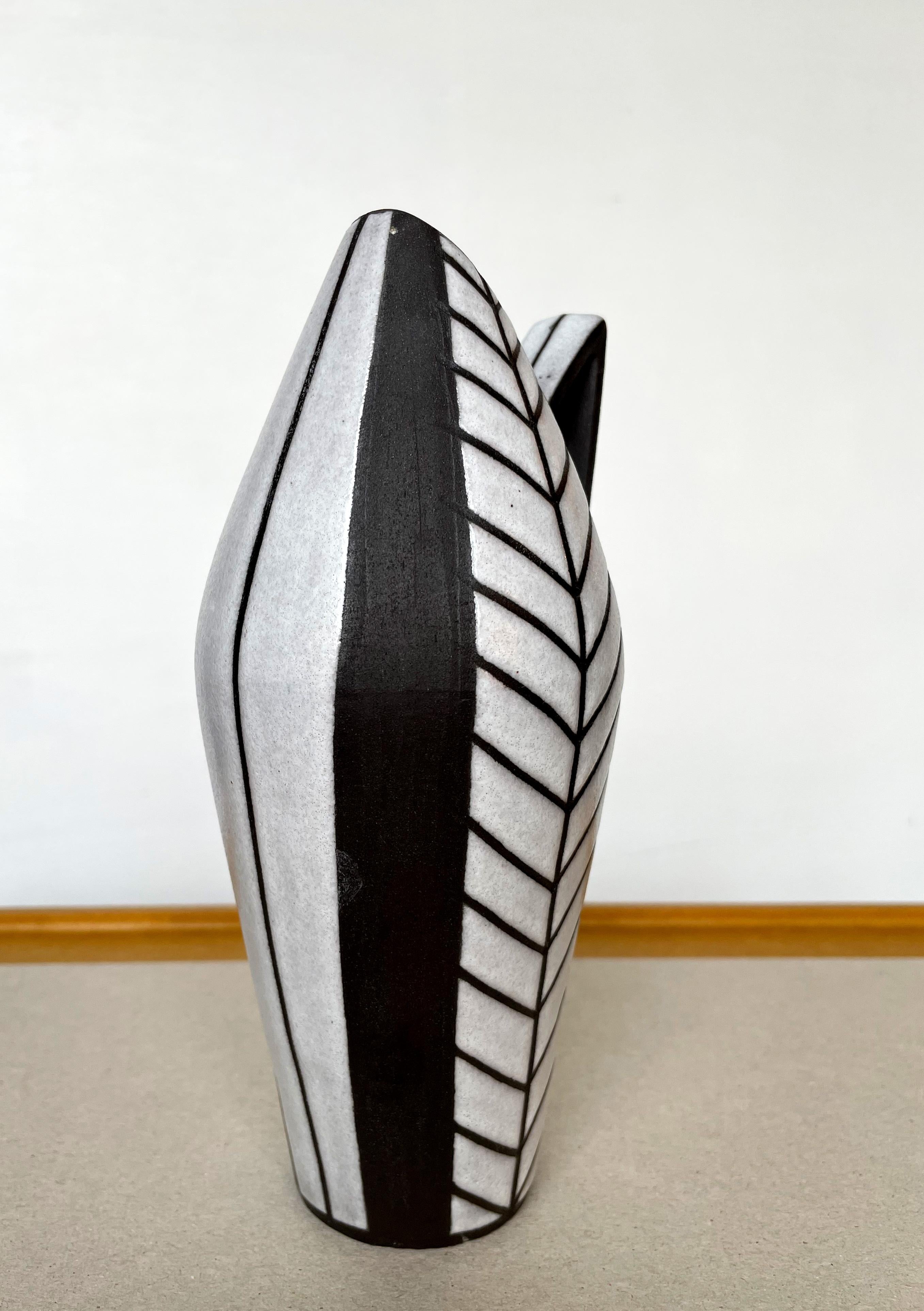 Handmade Danish Mid-Century Modern vase with strong graphic decor from the Tribal / Harlekin series by Marianne Starck (1931-2007) in the 1950s. Shiny bone white glaze with hand-carved graphic lines on the curved, elegant shape in raw anthracite