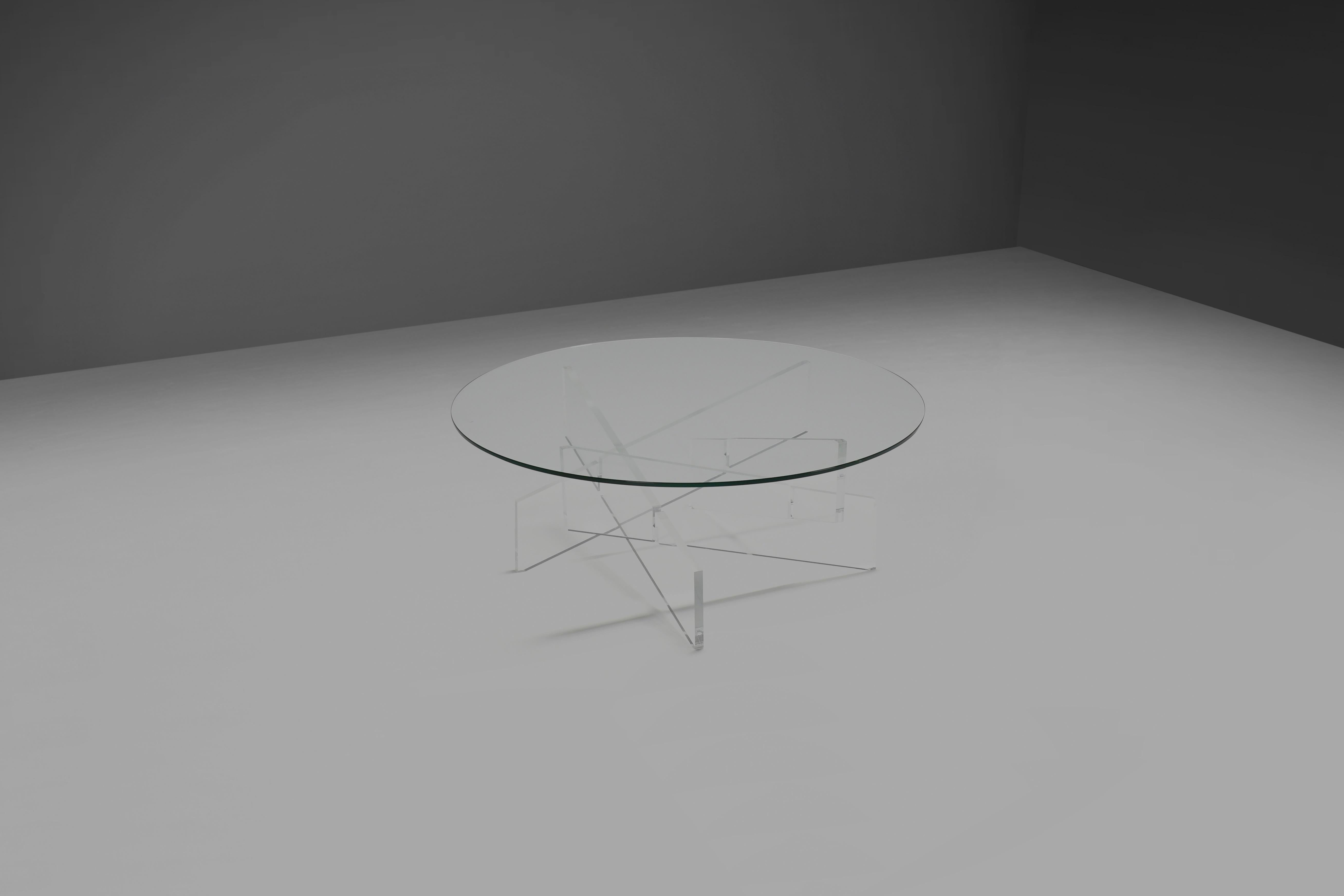 Rare table basse graphique en excellent état. 

La table a un plateau rond en verre qui est soutenu par une base formée par des poutres croisées en lucite qui donnent un bel effet. 

Toute la table est transparente, ce qui la rend très