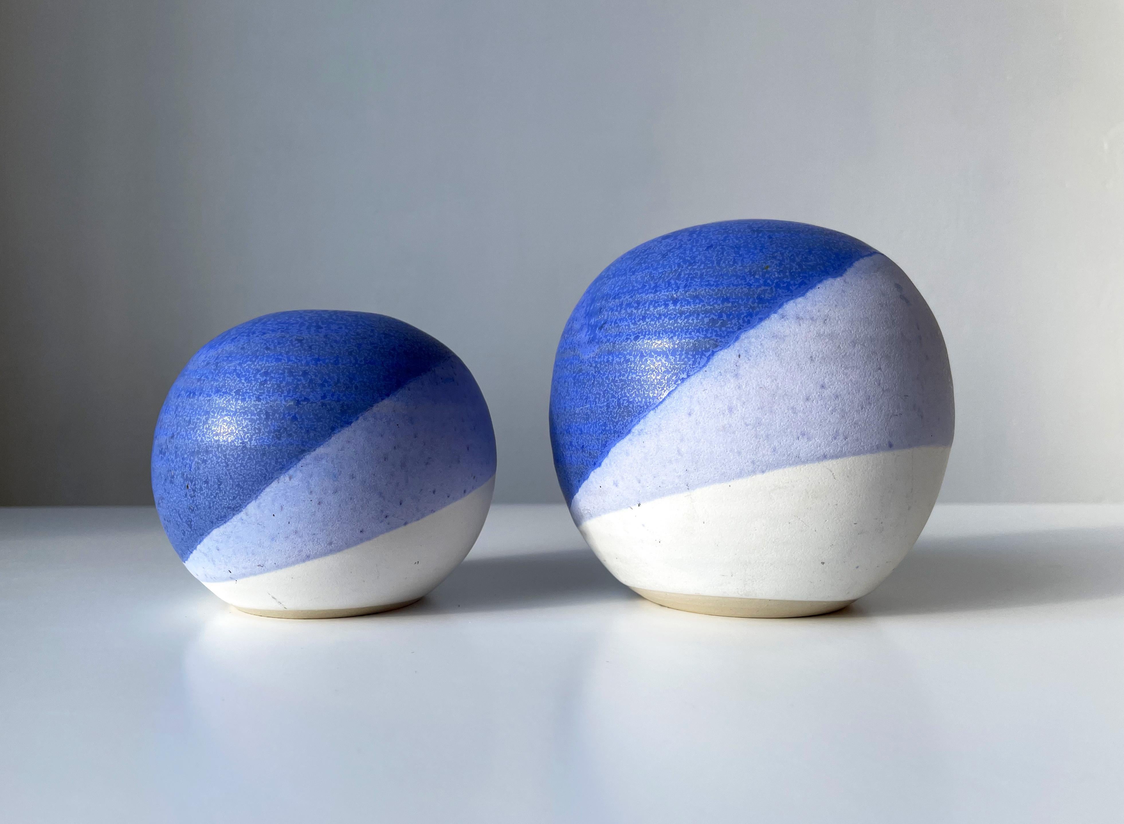 Set of two Danish modernist ceramic globe vases or candle holders. Shiny blue glaze over matte lilac and white glaze in asymmetrical stripes accentuating the round shape. Manufactured in Denmark by KN Keramik in the 1980s. Both vases signed under