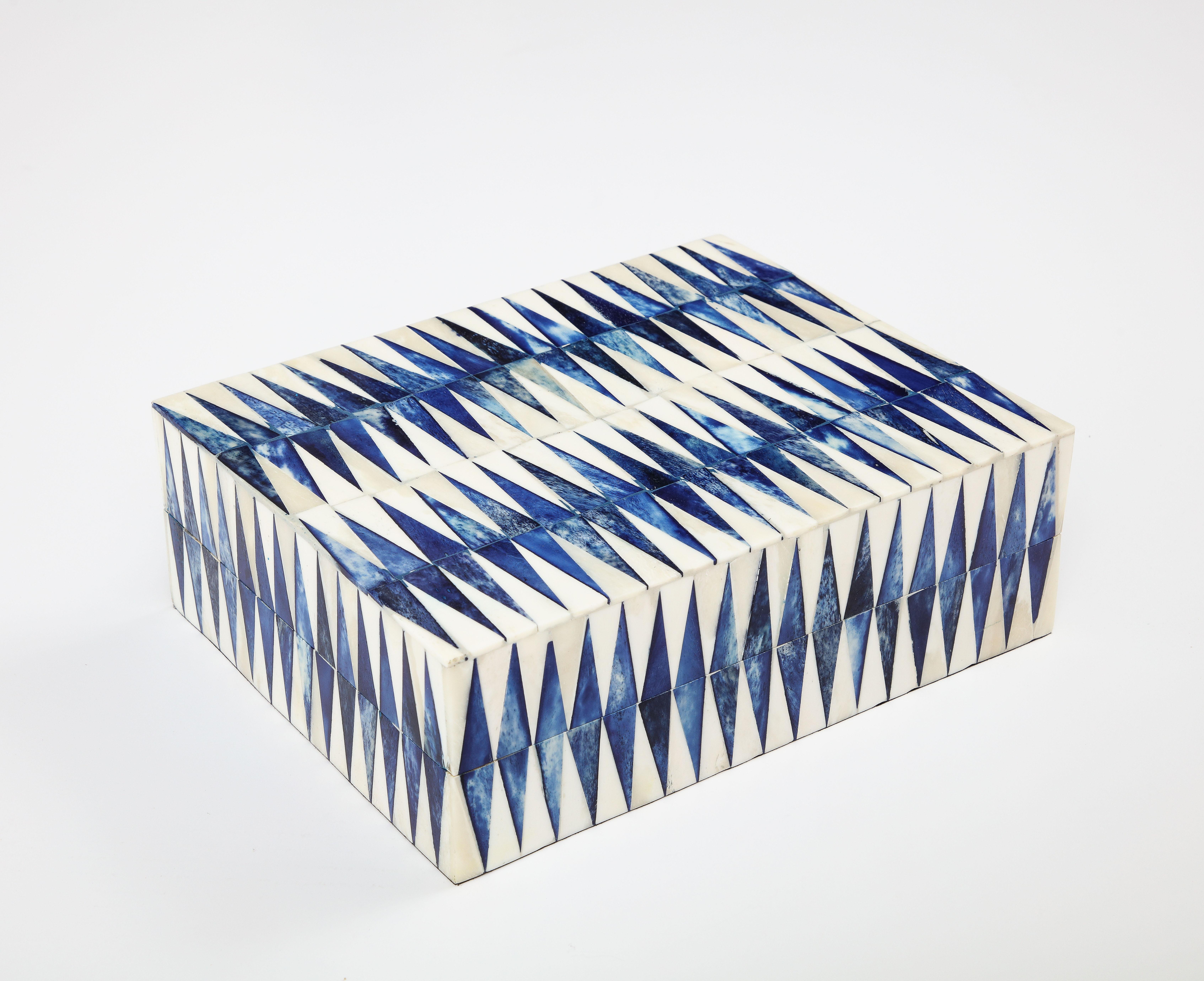 Caja de recuerdos con motivos gráficos revestida de hueso teñido de azul tinta y natural. Las baldosas se colocan a mano sobre una caja de madera.