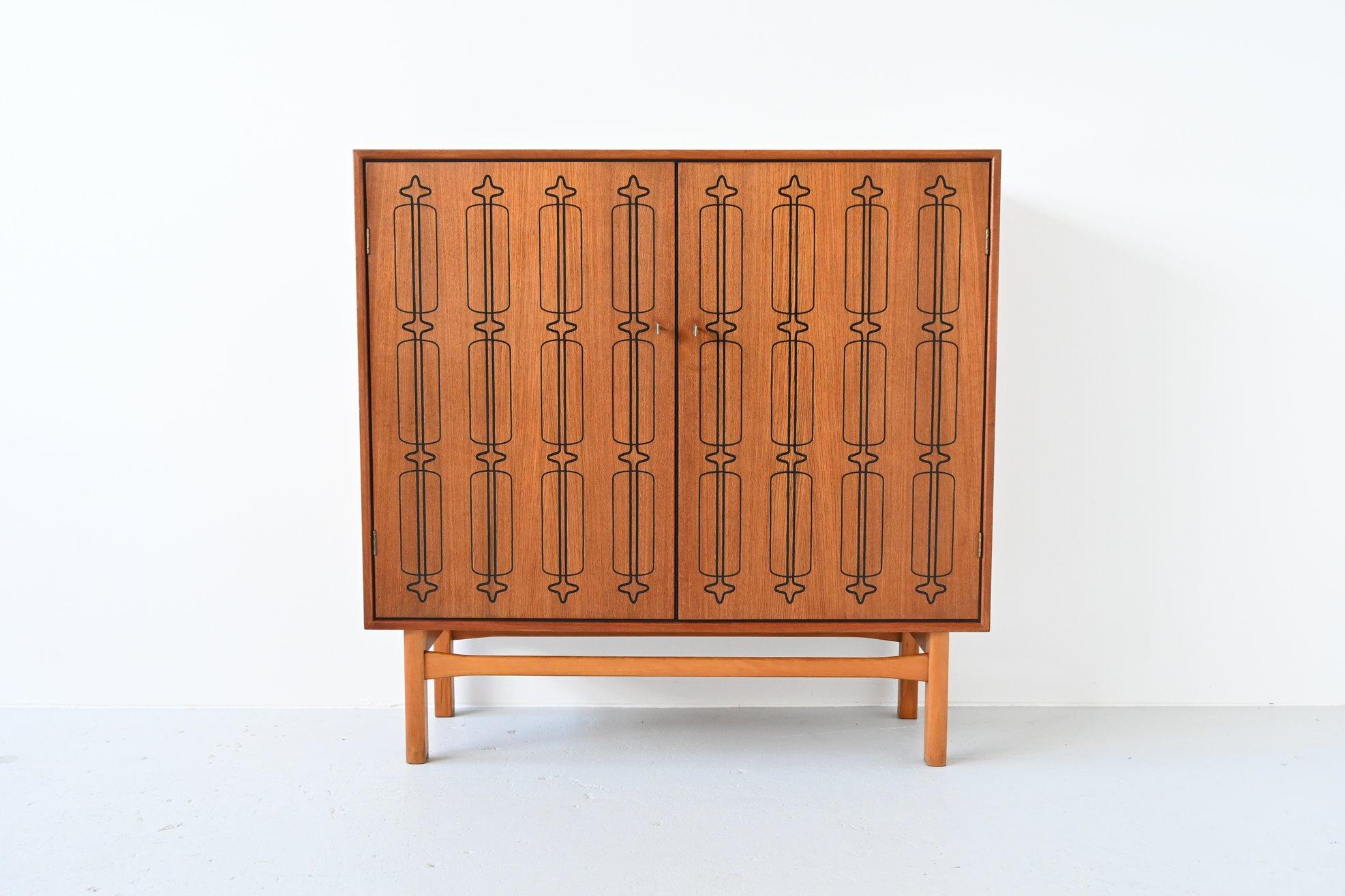 Beautiful and unique Scandinavian cabinet, Denmark 1960. This very nice unusual cabinet is made of high quality veneered teak wood with a great graphic pattern on the doors. The base is made of solid beech wood. Inside this cabinet there is a plenty
