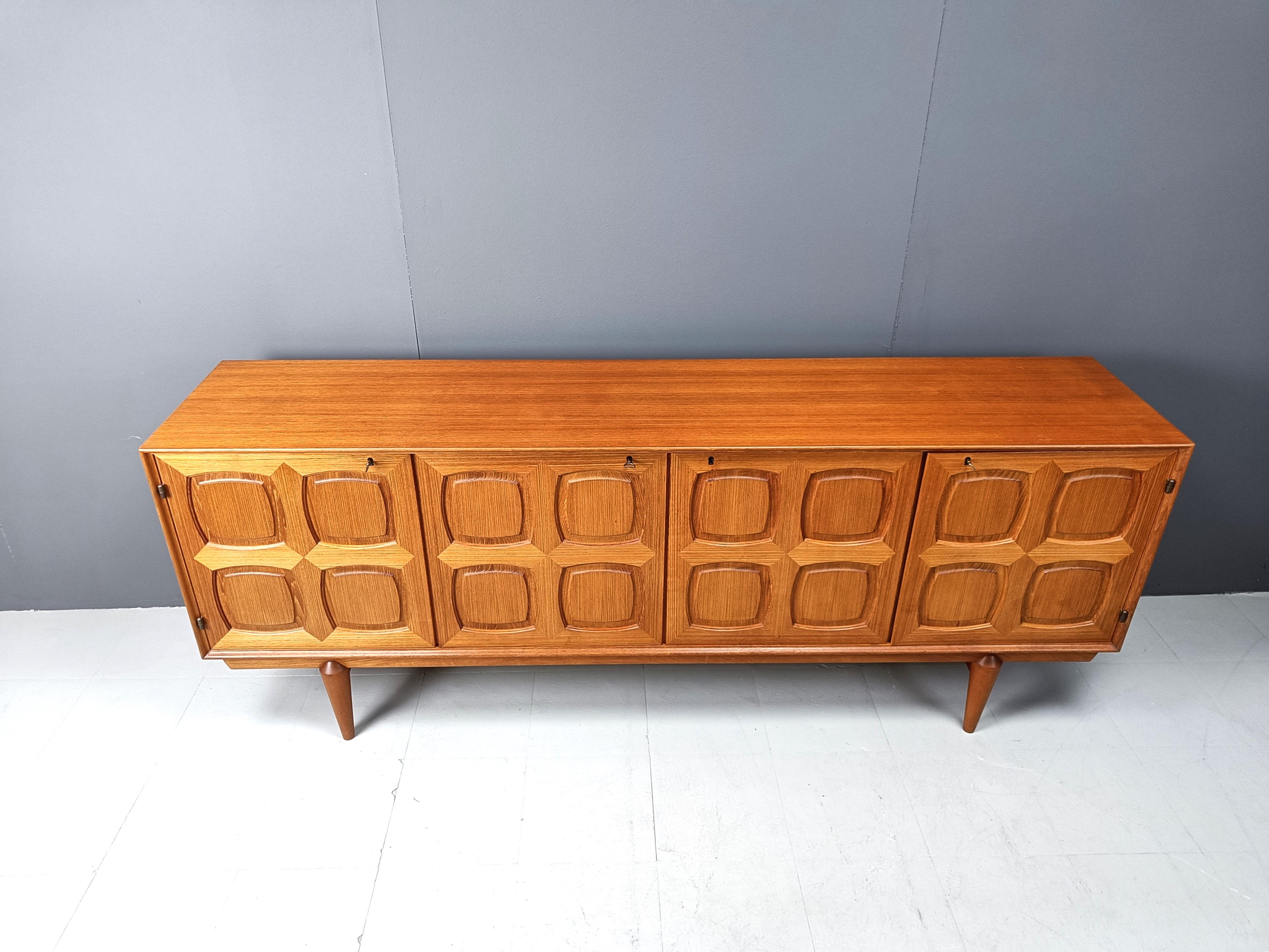 Striking graphic sideboard designed by Rastad & Relling and manufactured by Gustav Bahus, Denmark 1960. 

The sideboard is made of teak wood and has very nice graphic panel doors. 4 Doors with shelves behind and sliding shelves behind the right