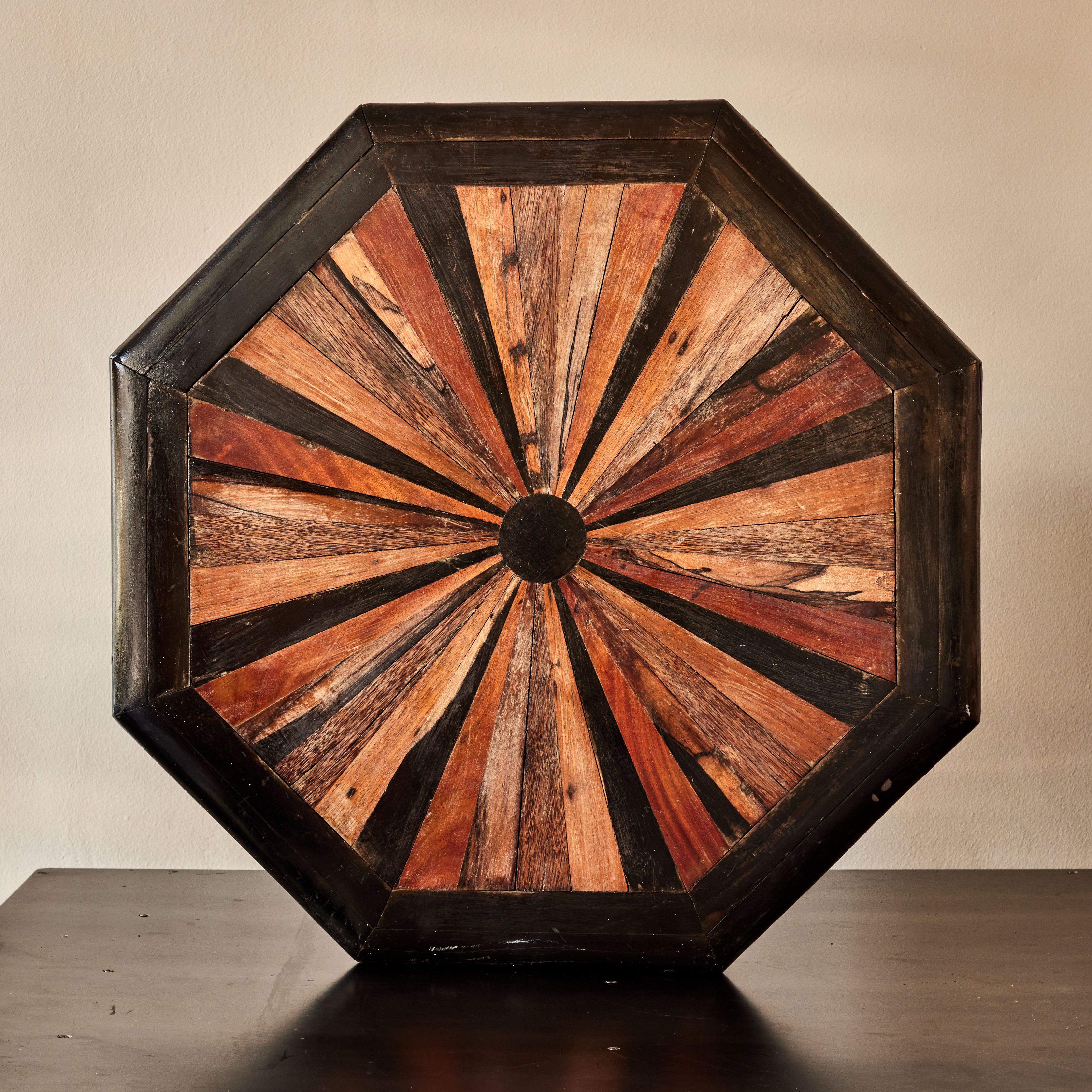 Octagonal wall panel of multi-colored wood specimens. A striking example of trompe l'ceil woodworking design, this early 19th-century English architectural element has a warm, graphic appeal. Featuring an ebonized border and sunburst pattern in