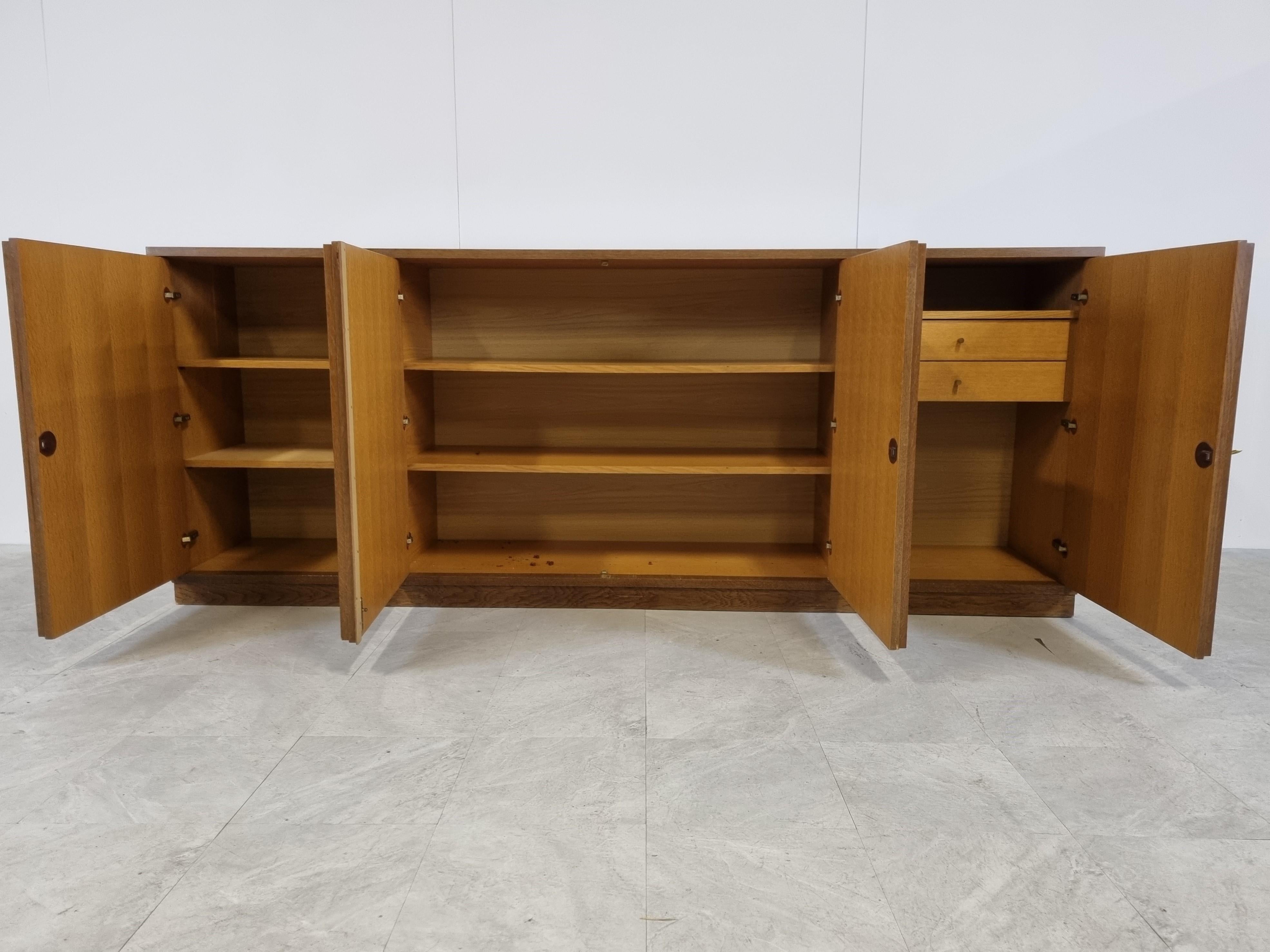 Brown brutalist two tone oak credenza with 4 graphical doors.

Beautiful timeless design and a real eye catcher for your living room.

This credenza provides plenty of storage space with two integrated drawers.

Good condition

1970s -