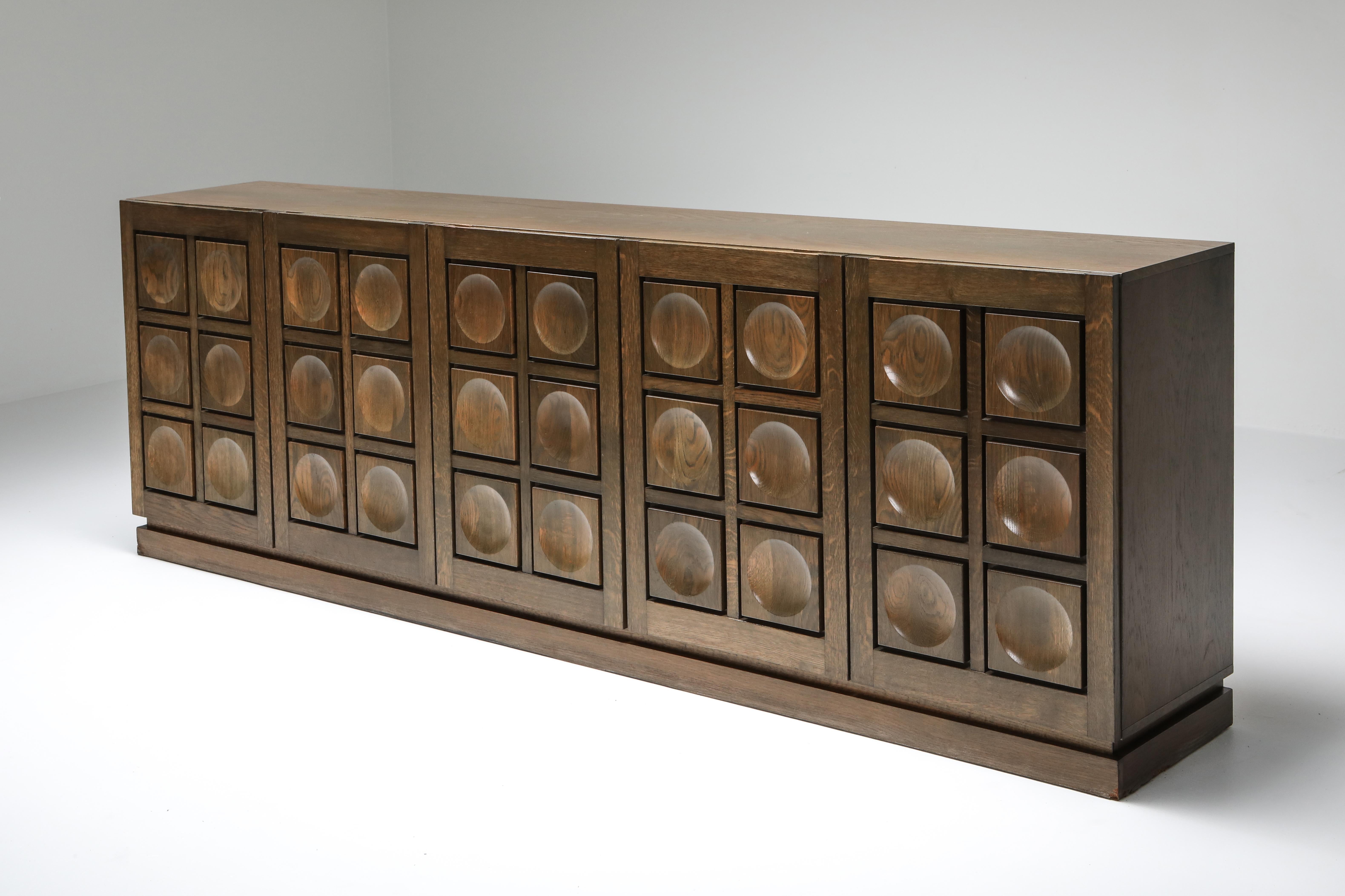 De Coene, Brutalist, five-door sideboard, Belgium, 1970s

The geometrical door panels are typical for the era.
The grain of the oak really jumps to the eye.

Would fit well in a Hollywood Regency decor as in a more naturalist
