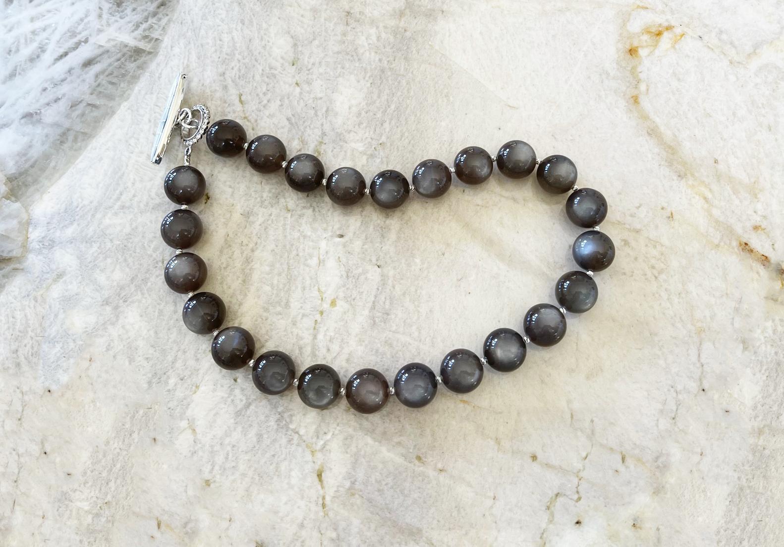Absolutely breathtaking shimmering chatoyant top grade dark graphite gray moonstone necklace featuring natural 16mm round gray moonstone beads, sterling silver accent beads, and an elegant handmade toggle clasp with mother of pearl inlay.