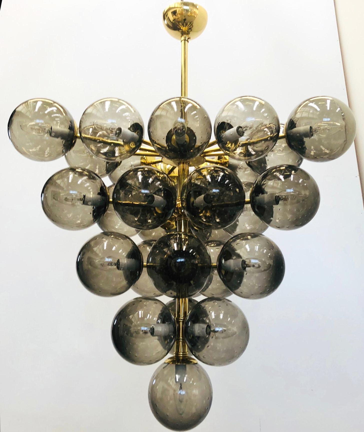 Lampadario italiano con globi in vetro di Murano fumé soffiati a mano con bolle all'interno del vetro con la tecnica delle Bollicine, montati su una struttura in ottone lucido / Disegnato da Fabio Bergomi per Fabio Ltd / Made in Italy
31 luci / tipo