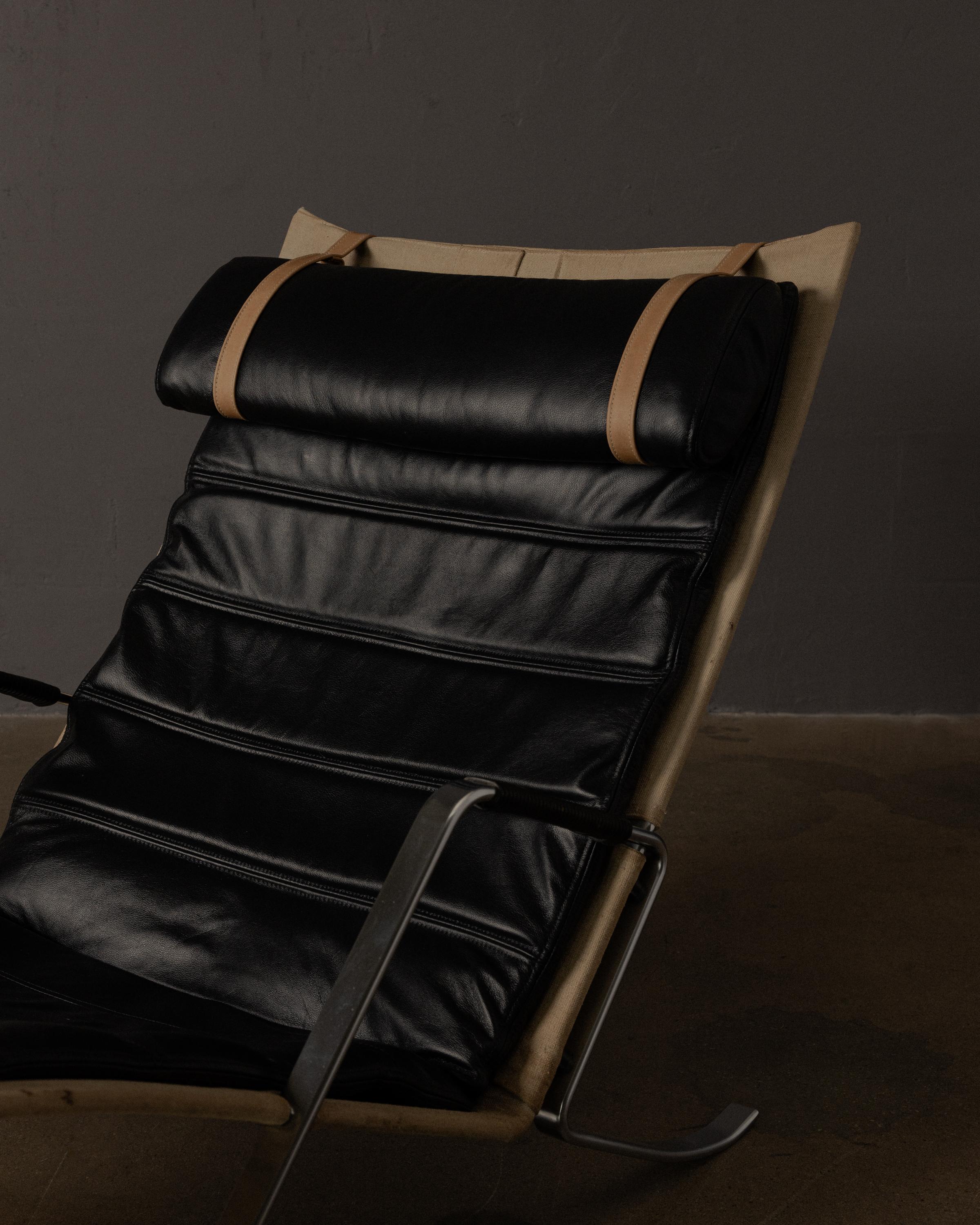An iconic mid-century design by Preben Fabricius and Jørgen Kastholm, the Grasshopper chair features a sculptural stainless steel frame supporting a contoured canvas sling with original black leather cushion and headrest.