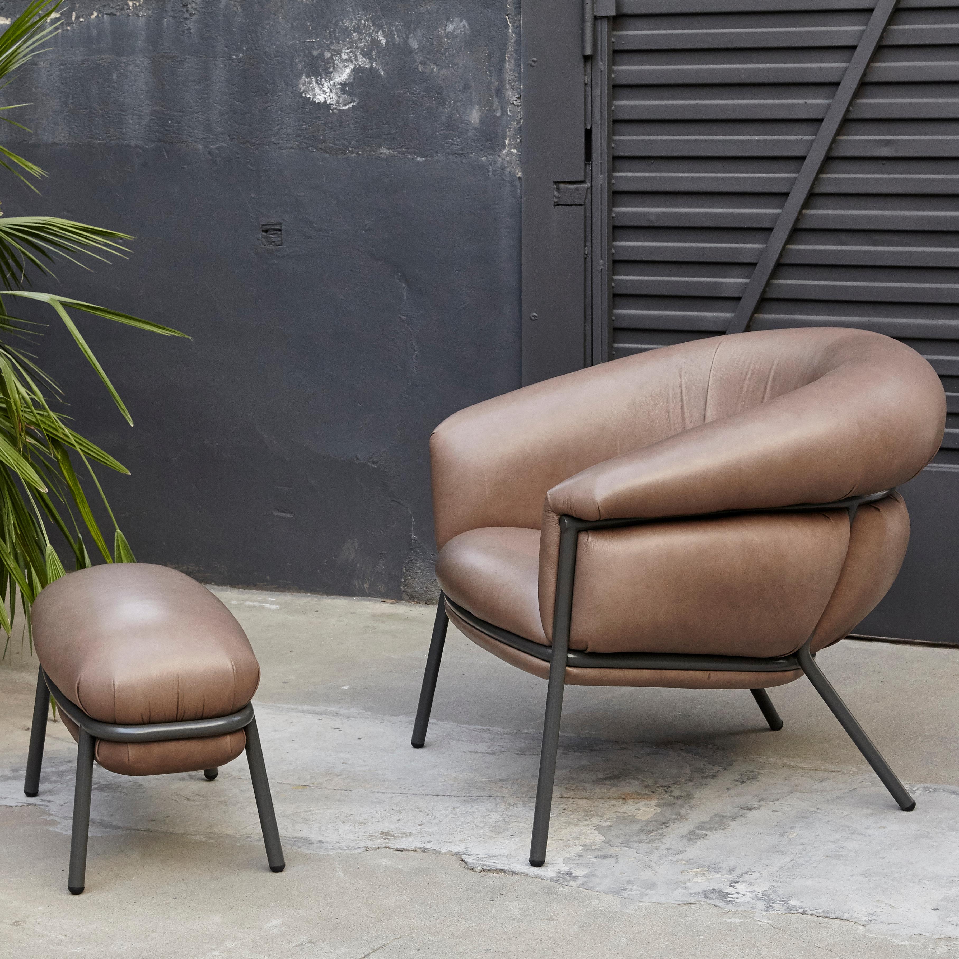 Armchair and foot stool designed by Stephen Bruks manufactured by BD Barcelona, circa 2018.

In good original condition with minor wear consistent with age and use.

An iron tubular (25mm) structured armchair. Seat and backrest upholstered in