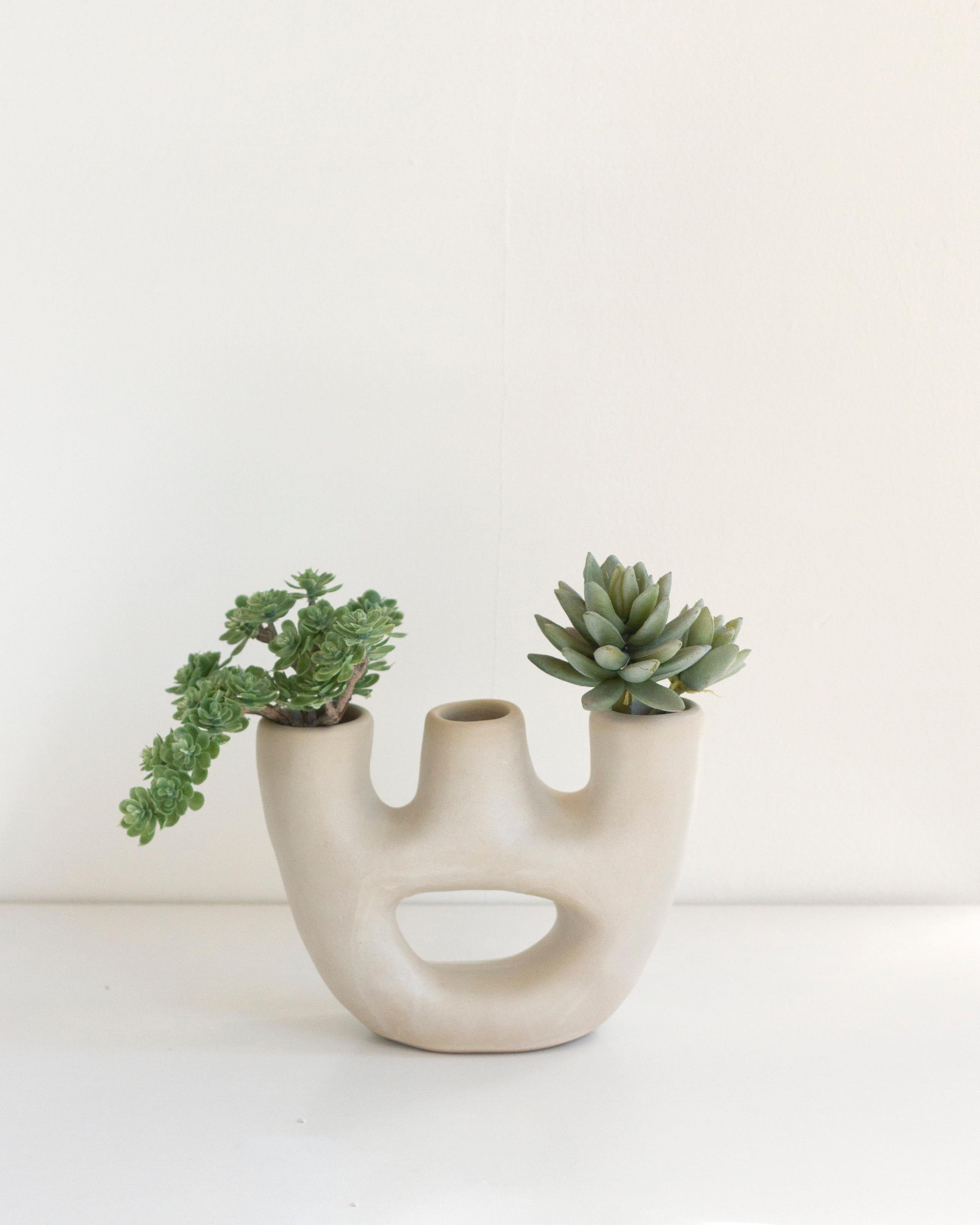 Diese minimalistische, handgefertigte Vase aus Ton eignet sich perfekt, um ein modernes, organisches Element in Ihr Heim zu bringen. Das Design dieser Vase ist von Kerzenhaltern inspiriert und hat drei Öffnungen, die ihr eine einzigartige Note