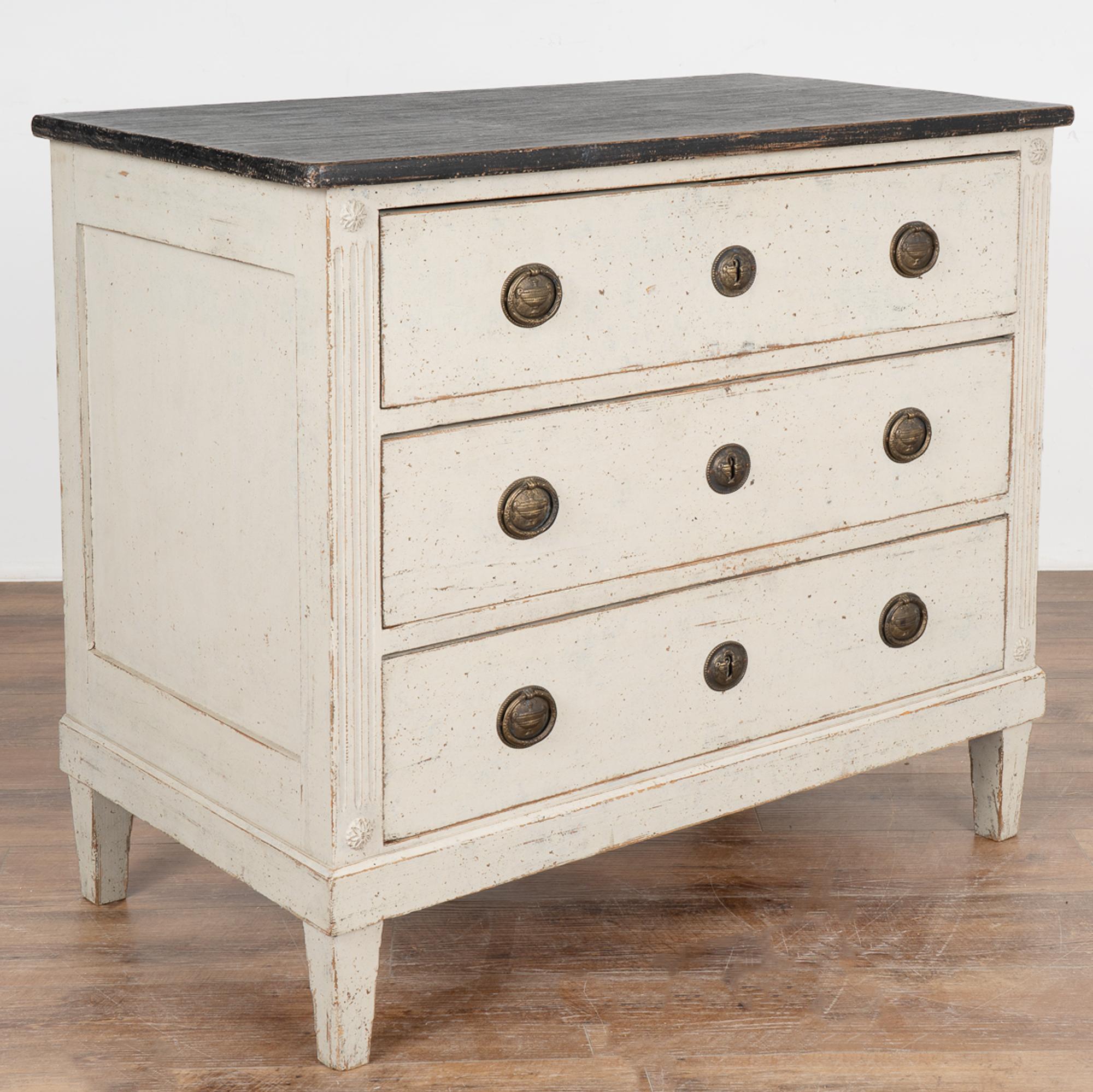 Gustavian style gray painted pine chest of three drawers with contrasting black painted top.
Newer professionally applied and layered gray painted finish, lightly distressed to fit age and grace of this lovely chest.
Sides have simple fluted
