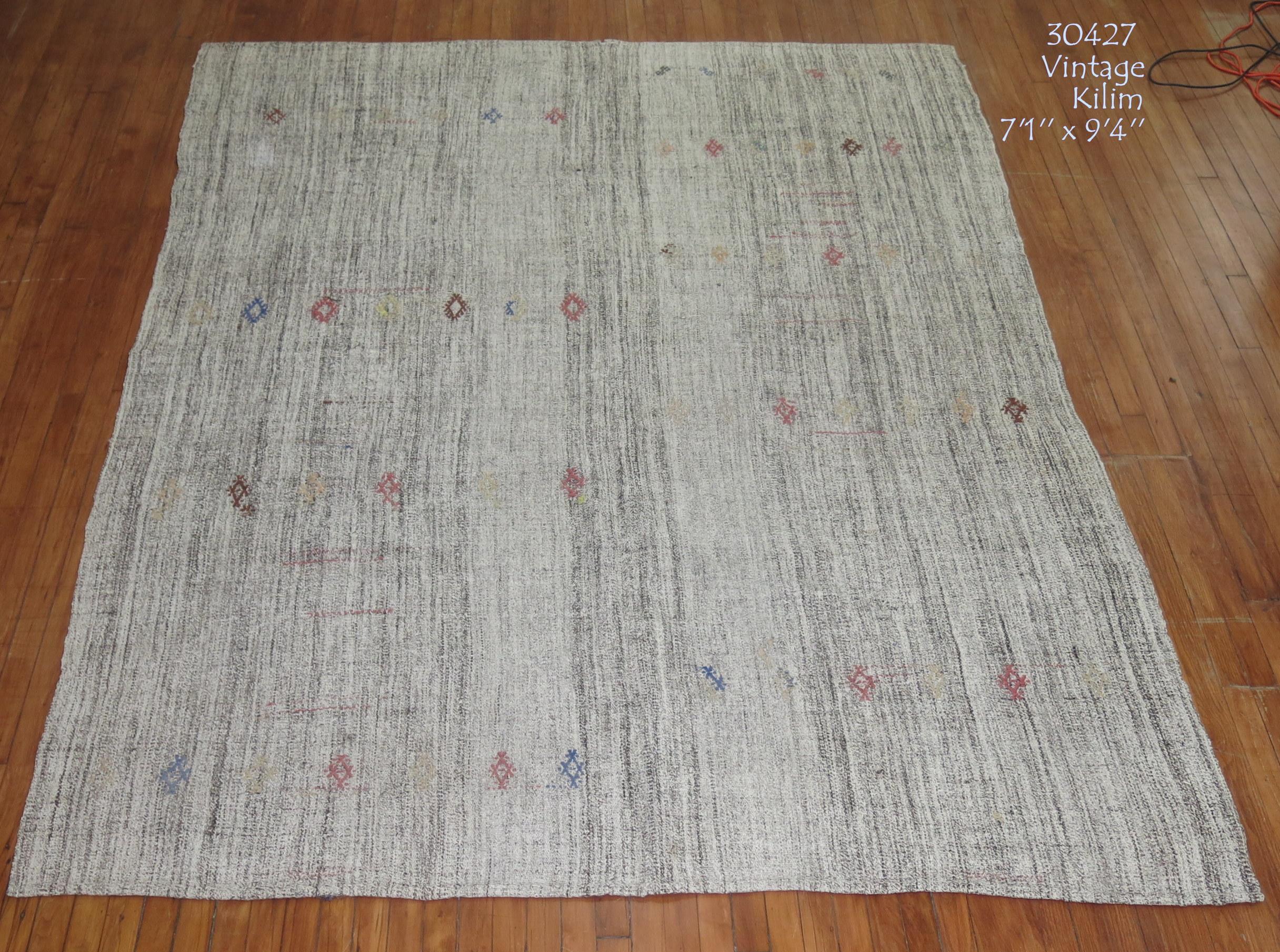 Midcentury Kilim with an abrashed gray/silver ground with small nomadic geometric motifs in earth accents. Measures: 7'1