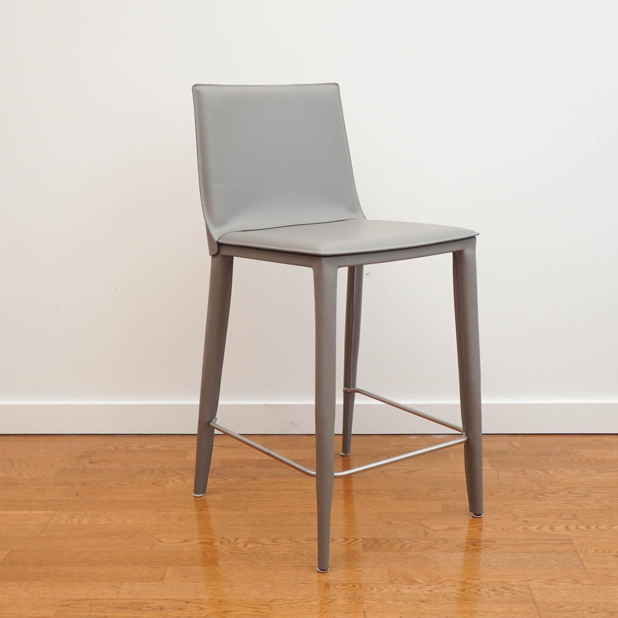 This leather-wrapped stool engineered for support and sophistication. The modern design creates a simple harmony. Lightly padded for added comfort, this stool is a beautiful addition to any space.