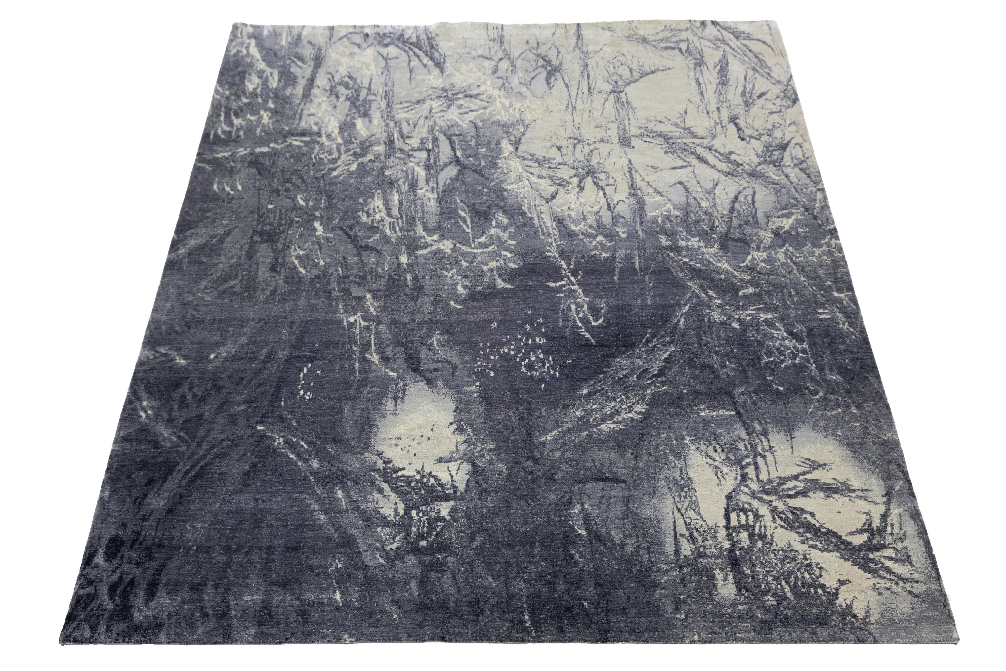 Questo tappeto contemporaneo annodato a mano vanta un sorprendente disegno astratto che attira immediatamente l'attenzione. Realizzato in seta pregiata, presenta uno sfondo di blu navy, grigio e avorio che ne accentua magnificamente gli intricati