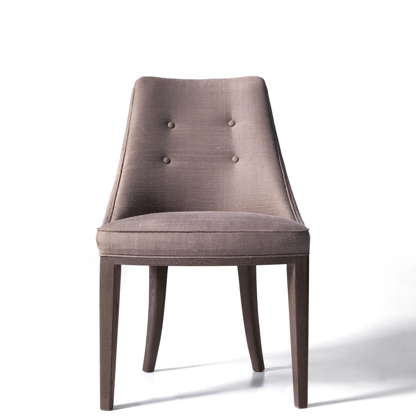 Ein weiches und einladendes Design zeichnet diesen raffinierten Stuhl aus, dessen robuste Hartholzstruktur einen großzügig gepolsterten Sitz und eine geschwungene Rückenlehne aufweist, die beide mit grauem Stoff mit subtilen Knopfakzenten bezogen