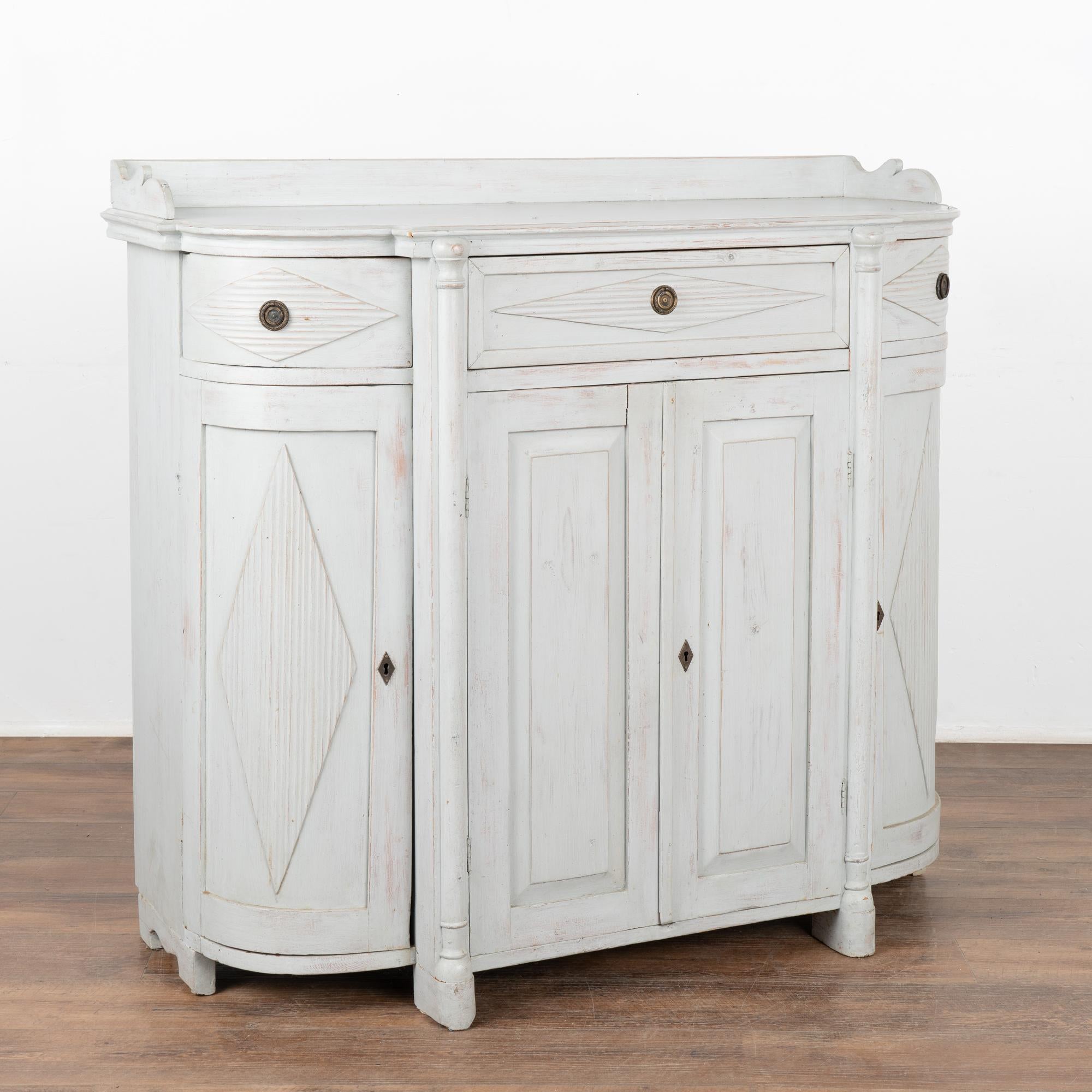 Tall Swedish Gustavian gray painted pine sideboard with attractive curved sides and traditional fluted diamond details.
The curved long cabinet doors and drawers make this cabinet a special find.
The later applied gray painted finish is lightly