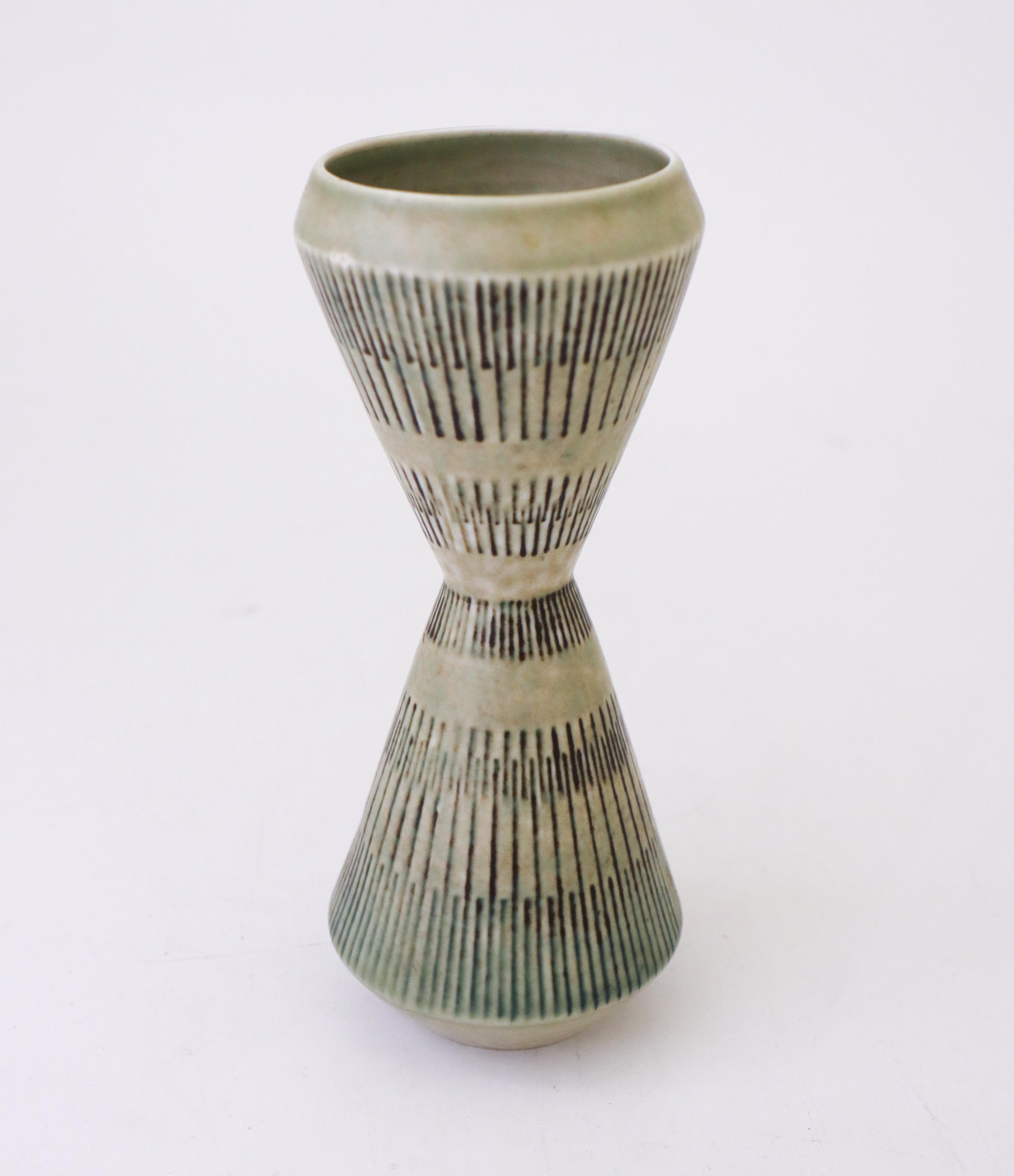 Un vase en céramique gris en forme de sablier conçu par Carl-Harry Stålhane chez Rörstrand. Le vase mesure 19,5 cm de haut et est en très bon état. Le vase est marqué comme étant de 2ème qualité. 

Carl-Harry Stålhane est l'un des grands noms de