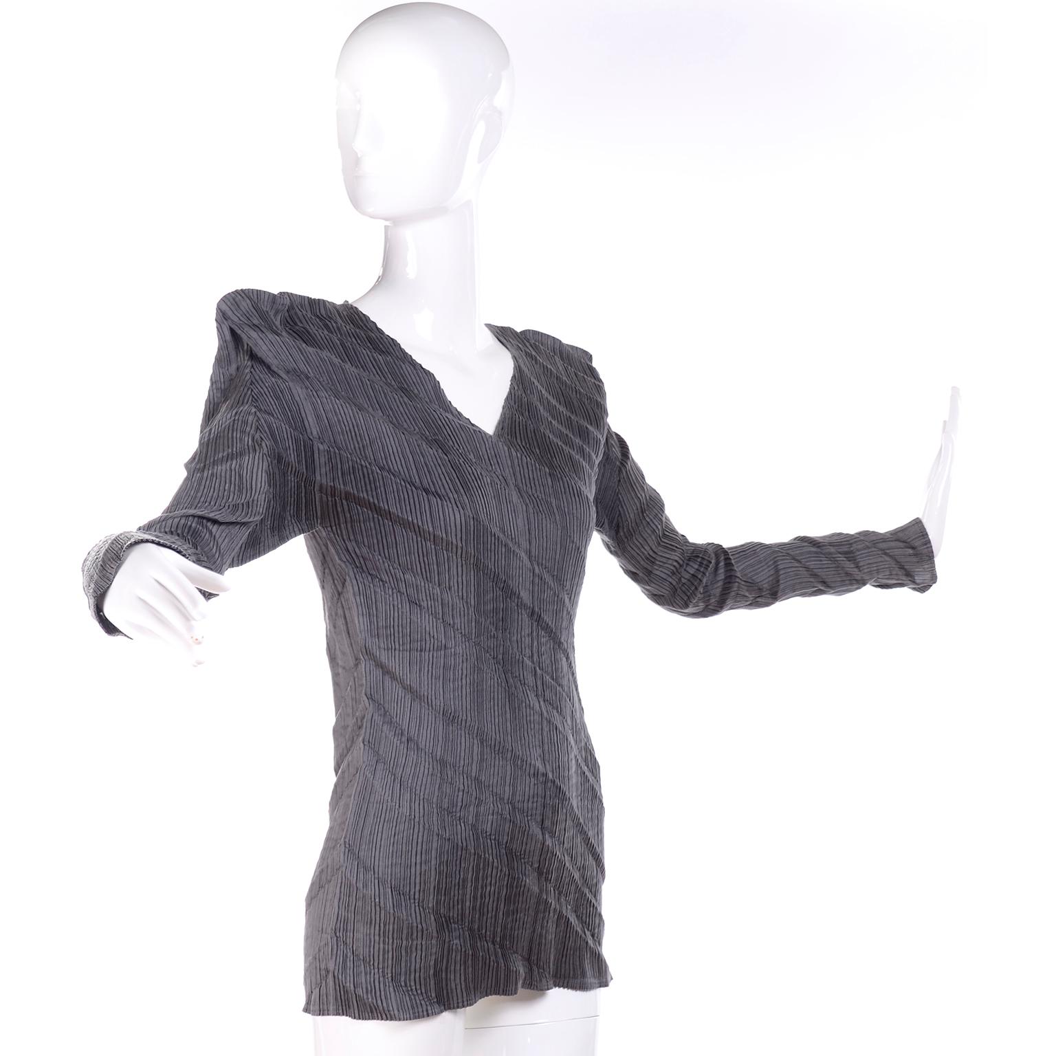 This is a fabulous Issey Miyake pleated top with avant garde asymmetrical shoulders in medium charcoal gray.  The top is pleated on the diagonal and is labeled a size Medium. This is one of many things we acquired when we purchased the estate of a