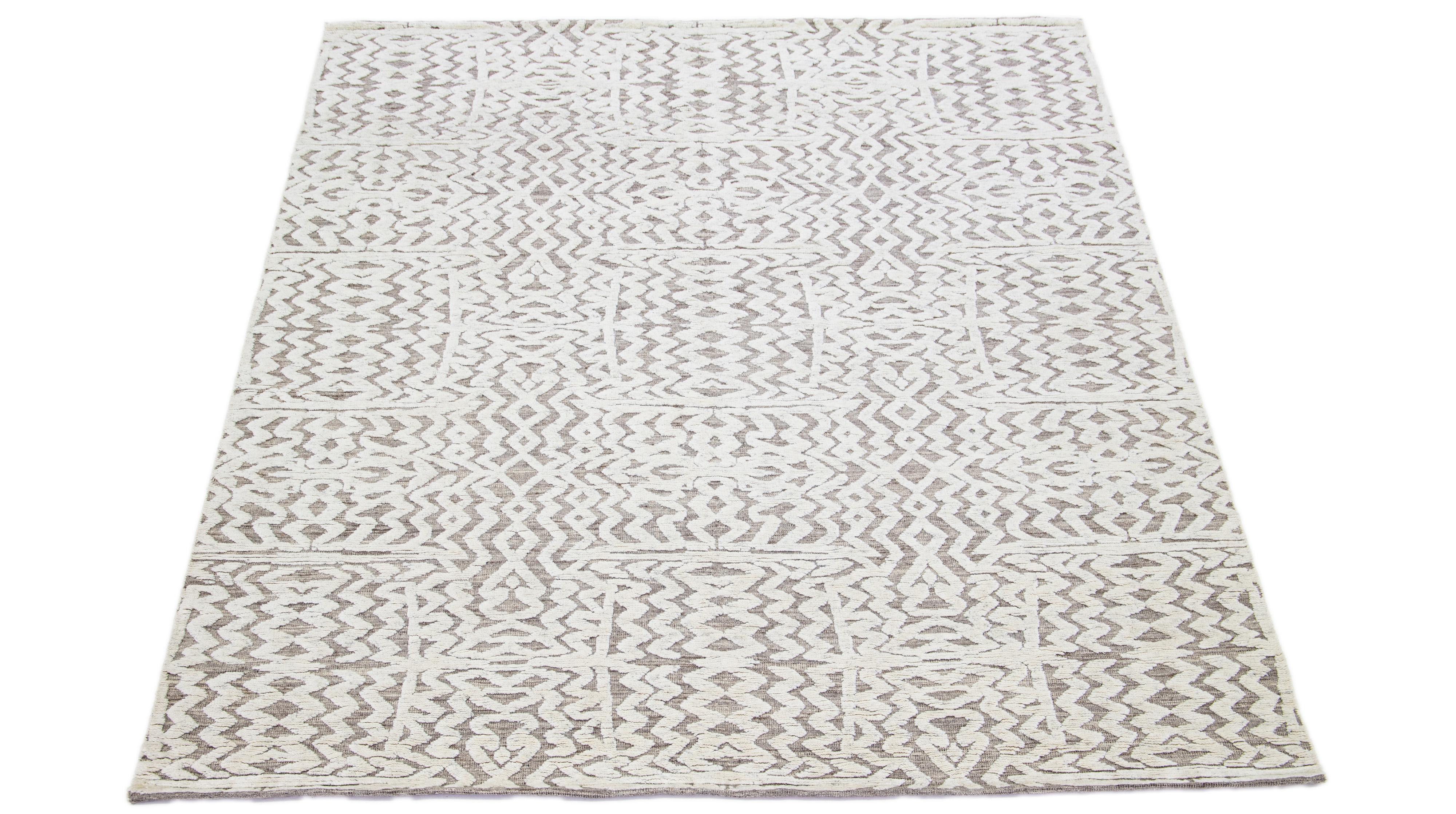 This wool rug, hand-knotted and boasting a contemporary Moroccan-inspired pattern, features subtle shades of Ivory set against a striking gray backdrop, producing a mesmerizing abstract design with seamless symmetry.

This rug measures 8'2