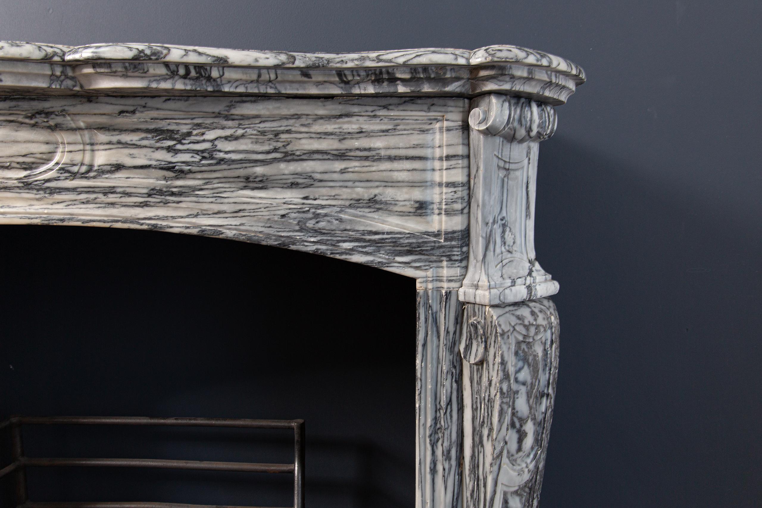 Gray antique front fireplace. The gray marble type where this fireplace is from buildings has a wild pattern. The veins in this type of stone provide a beautiful drawing. The fireplace has beautifully decorated consoles and a curved front. The top