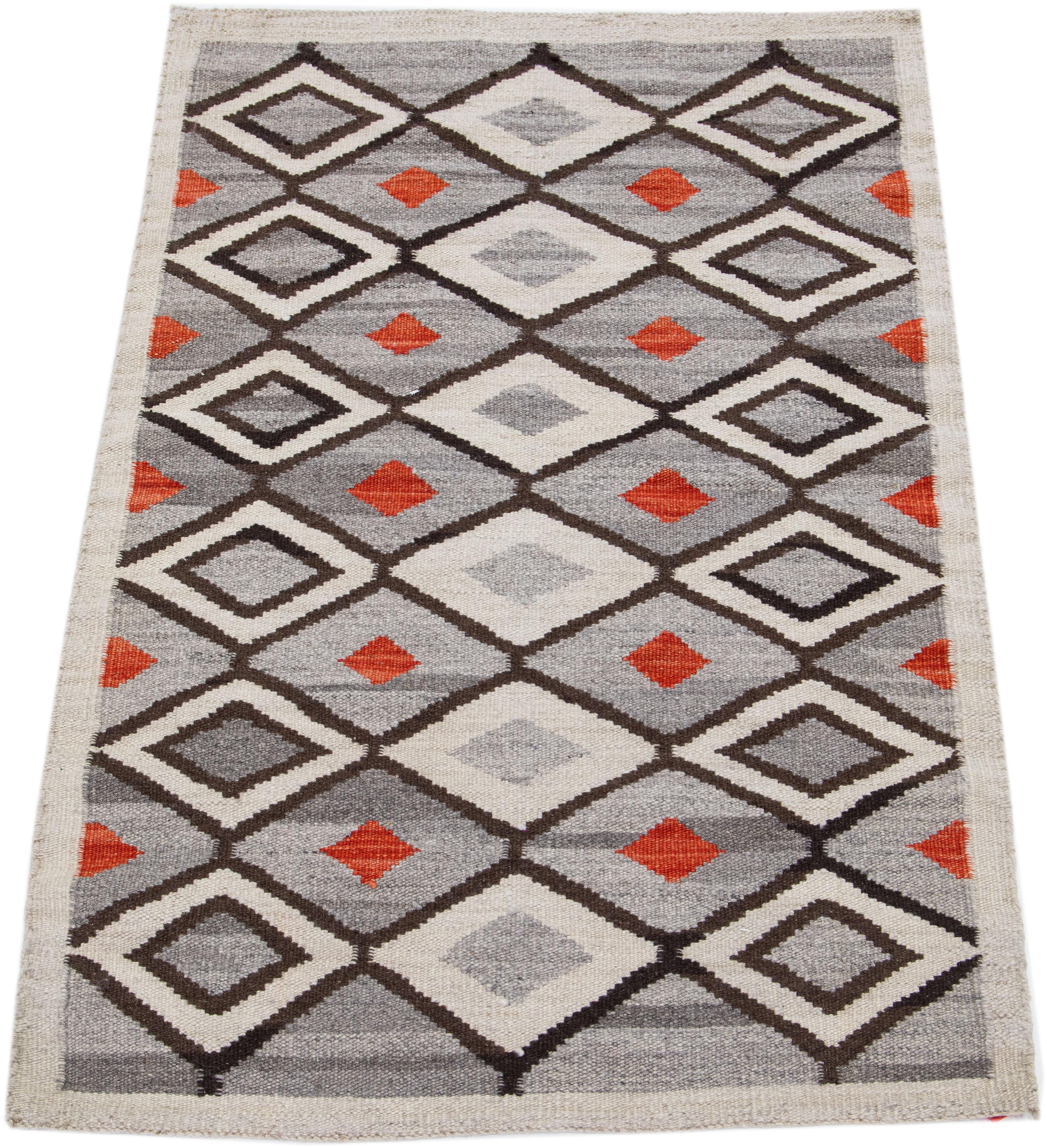 Magnifique tapis contemporain en laine tissée à plat, fait à la main, de style sud-ouest, avec un champ gris. Cette pièce présente des accents de beige, de marron et d'orange dans un motif géométrique omniprésent.

Ce tapis mesure : 3'2