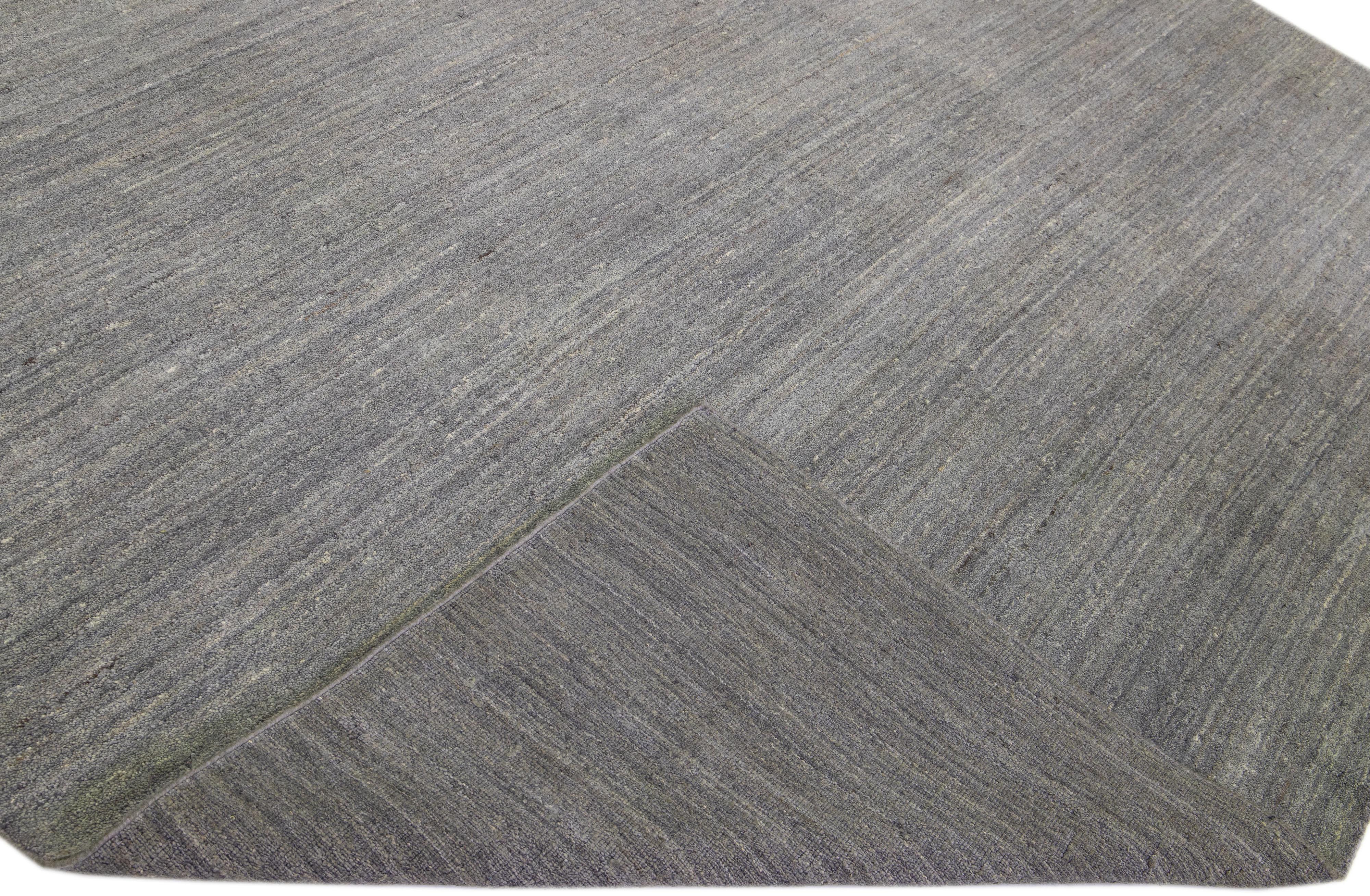Beautiful modern Gabbeh style hand-knotted wool rug with a grey field in a gorgeous solid design.

This rug measures: 9'11