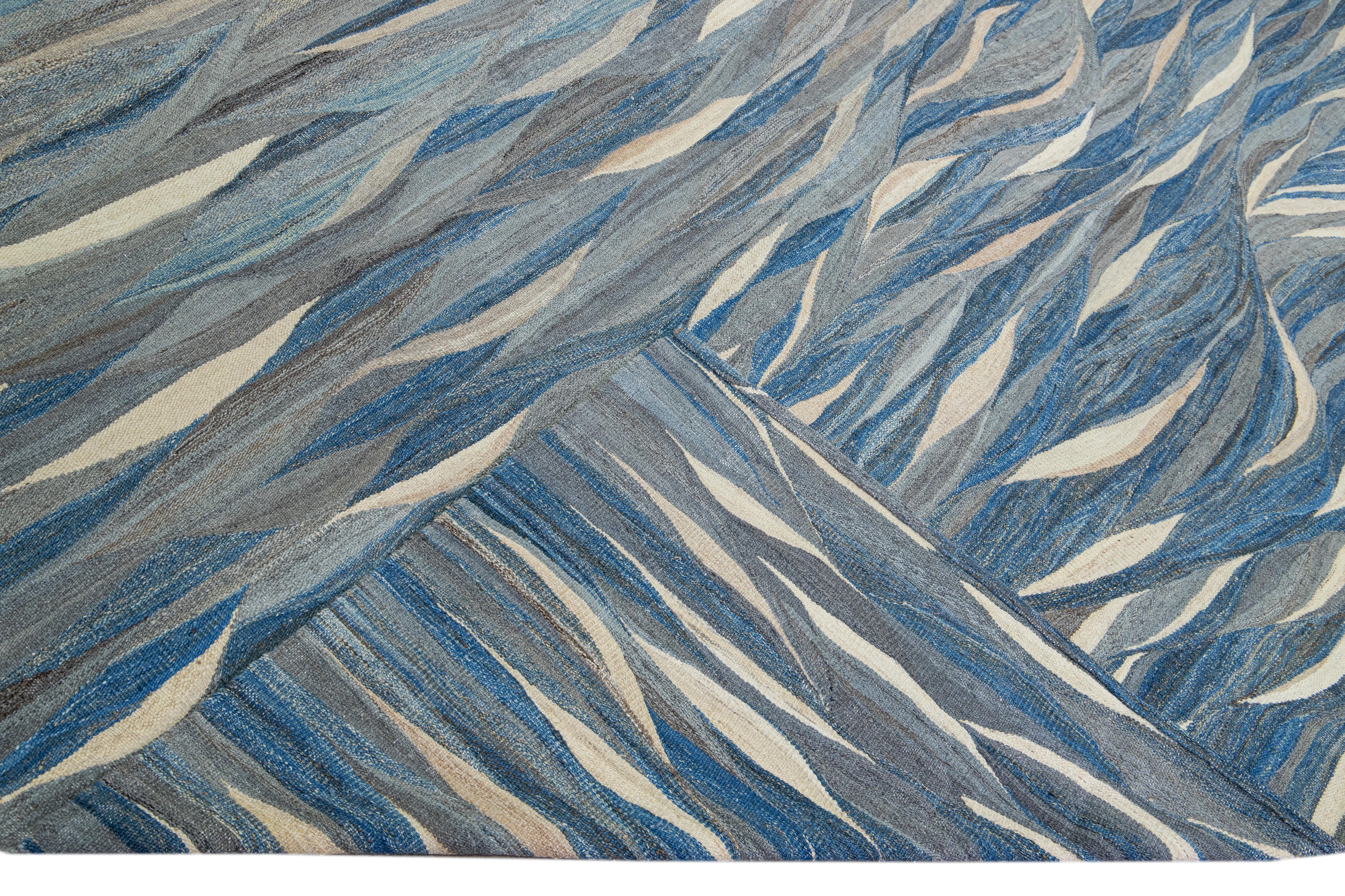 Magnifique tapis Kilim moderne en laine tissé à plat, fait à la main, avec un champ gris. Ce tapis Kilim a des accents bleus et beiges dans un magnifique design expressionniste abstrait.

Ce tapis mesure : 12' x 14'9