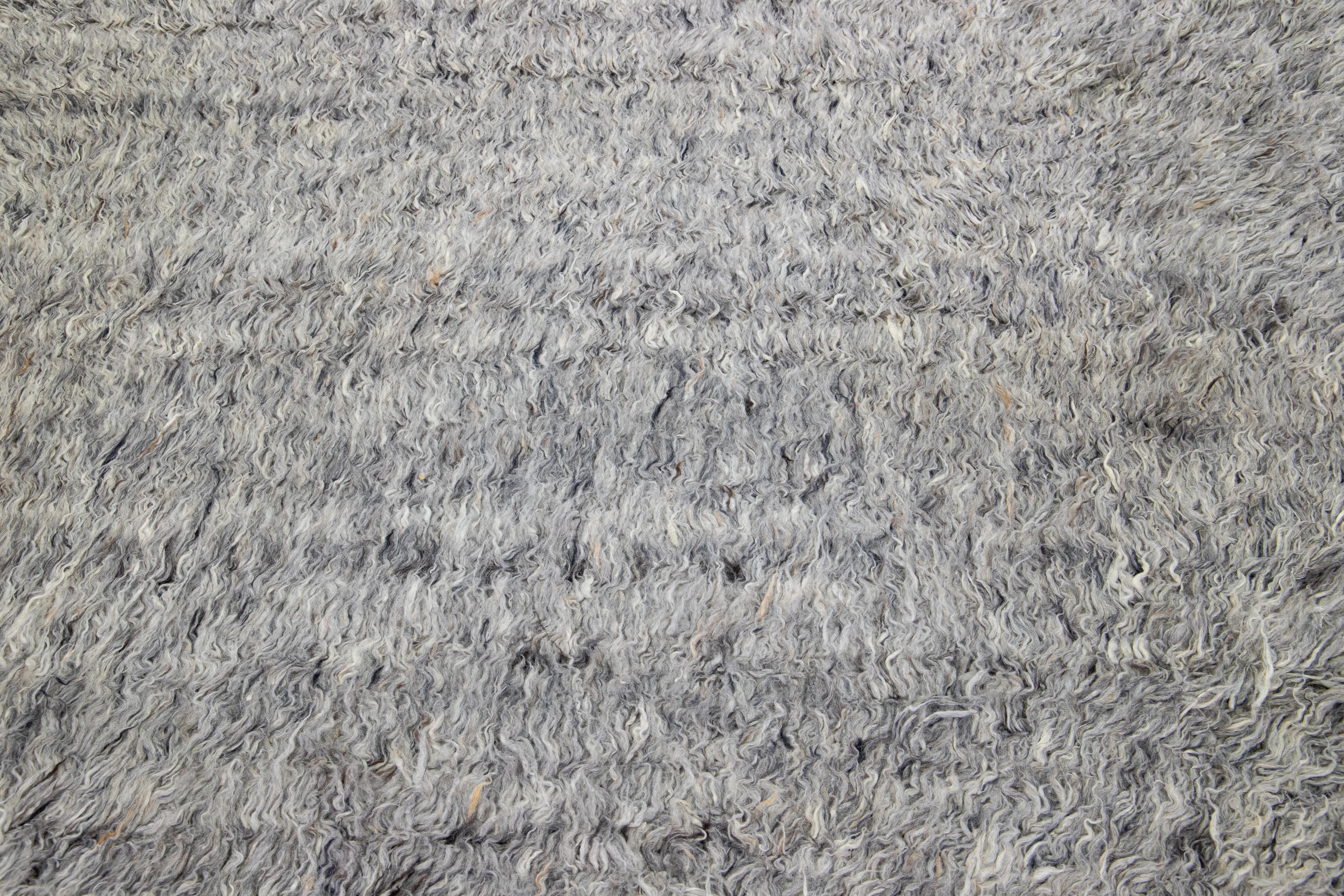 Dieser handgeknüpfte Teppich aus Bio-Wolle hat einen schicken marokkanischen Stil. Es zeigt einen spannenden Hintergrund in Grautönen.

Dieser Teppich misst 8'2' x 10'3