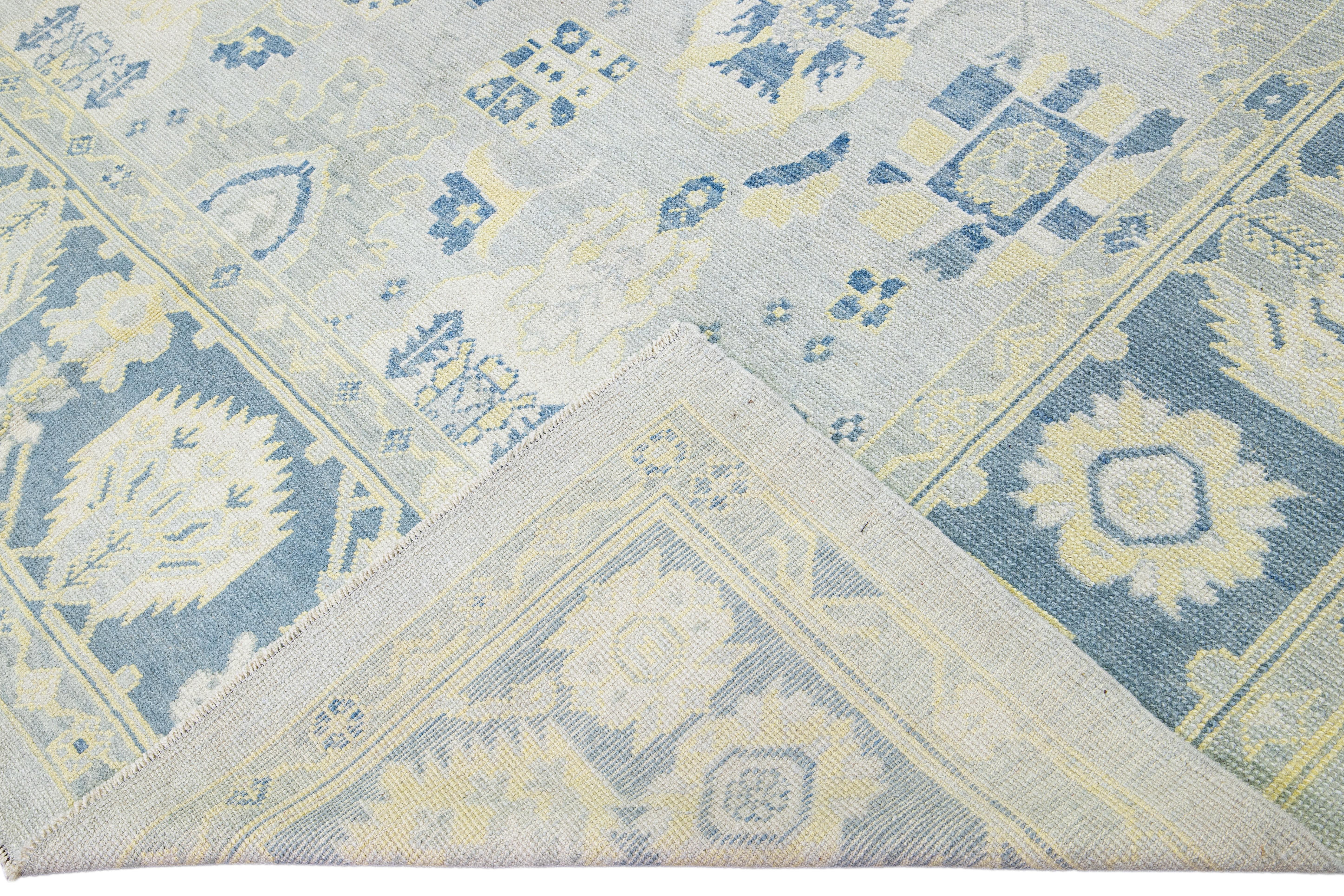 Beautiful modern Oushak hand-knotted wool rug with a gray field. This Oushak rug has blue and yellow accents that feature a gorgeous geometric floral motif. 

This rug measures: 9' x 12'4