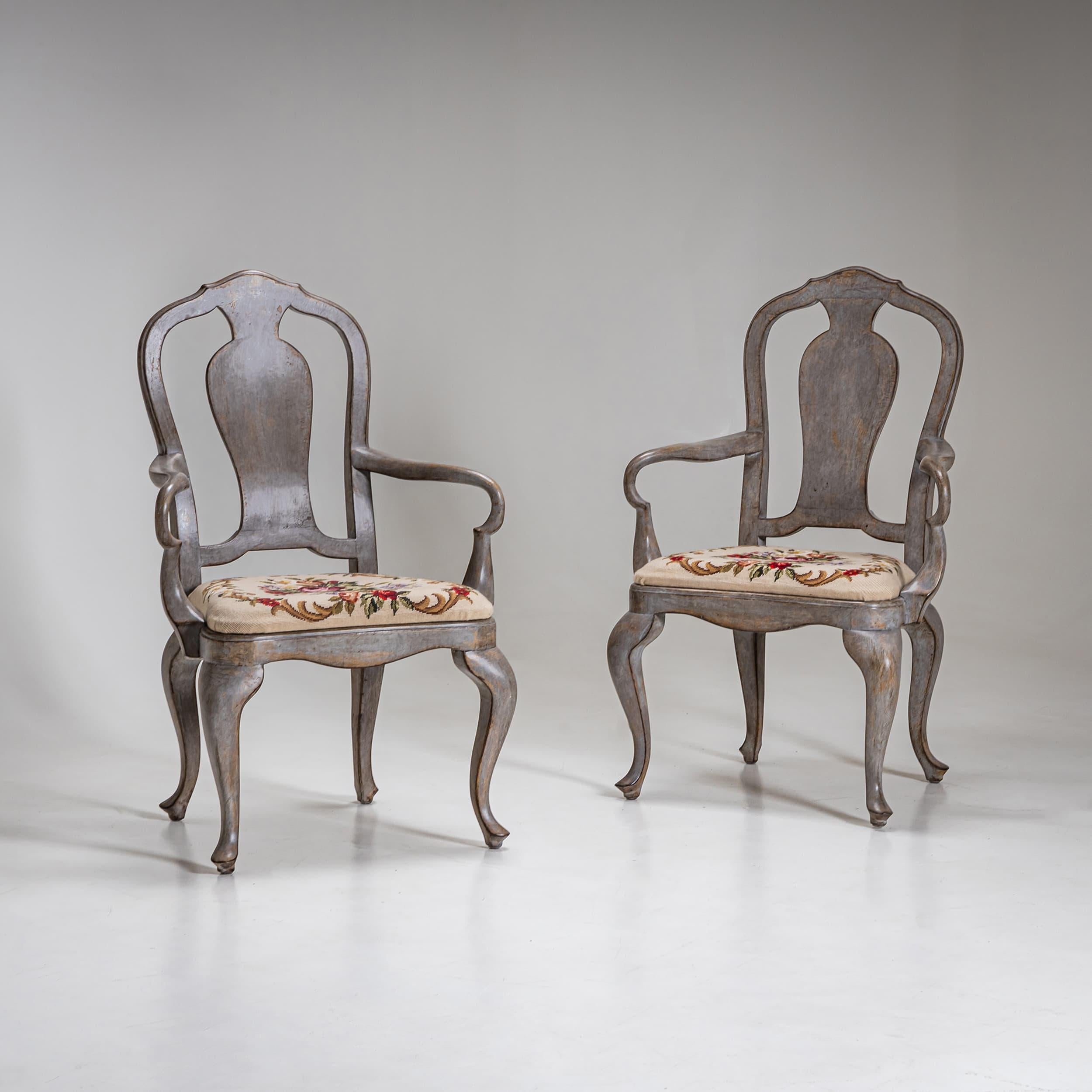 Elegante coppia di poltrone del XIX secolo con braccioli graziosamente curvati e gambe cabriole in stile barocco. Gli schienali scolpiti e la nuova verniciatura grigia ne esaltano il fascino storico. Le sedute sono rivestite da cuscini ricamati con