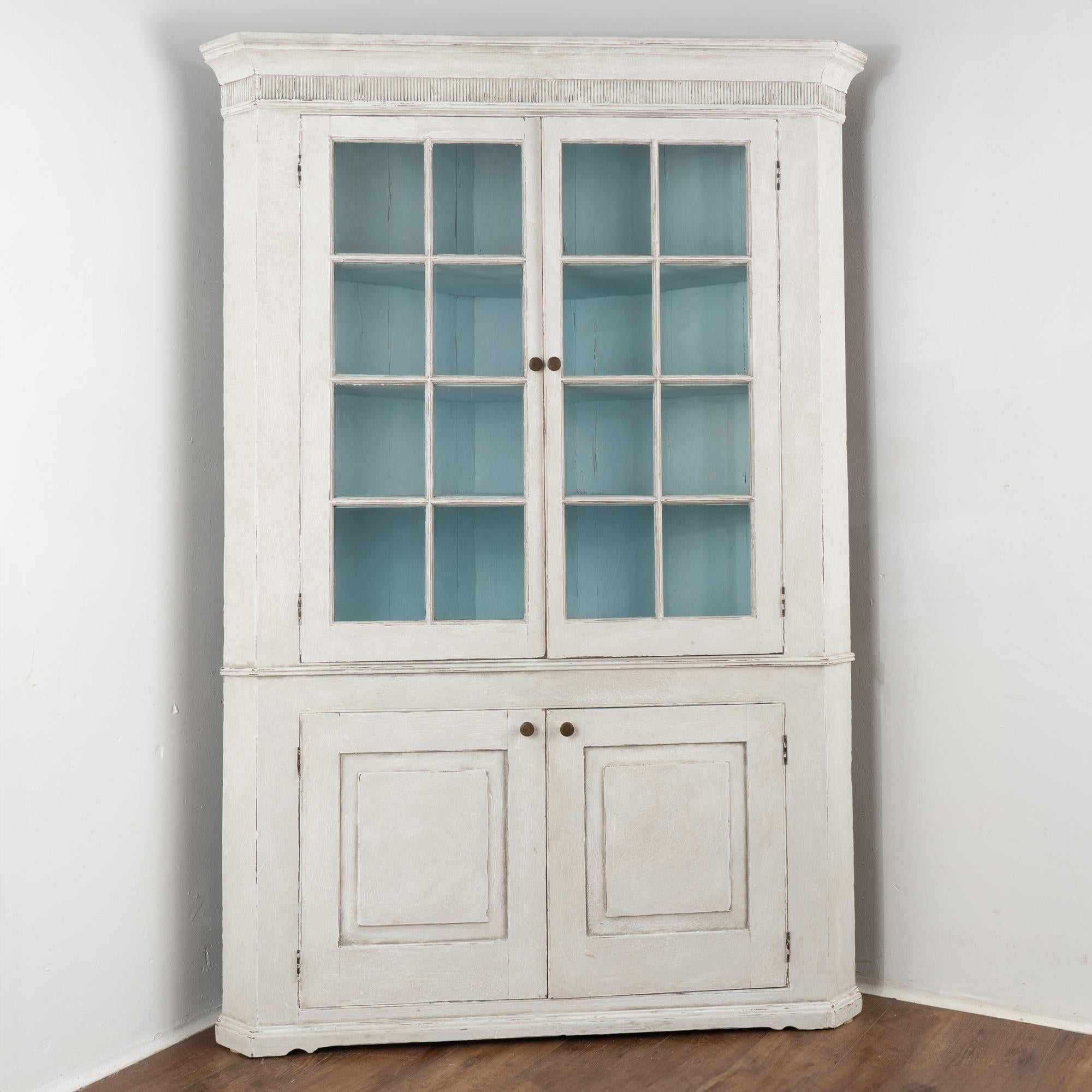 This pine corner cabinet has lovely pane glass upper doors allowing beautiful display of any collection held within. 
This large cabinet is built as one piece (it does not break down into sections) and reaches 7' tall with a simple crown and fluted
