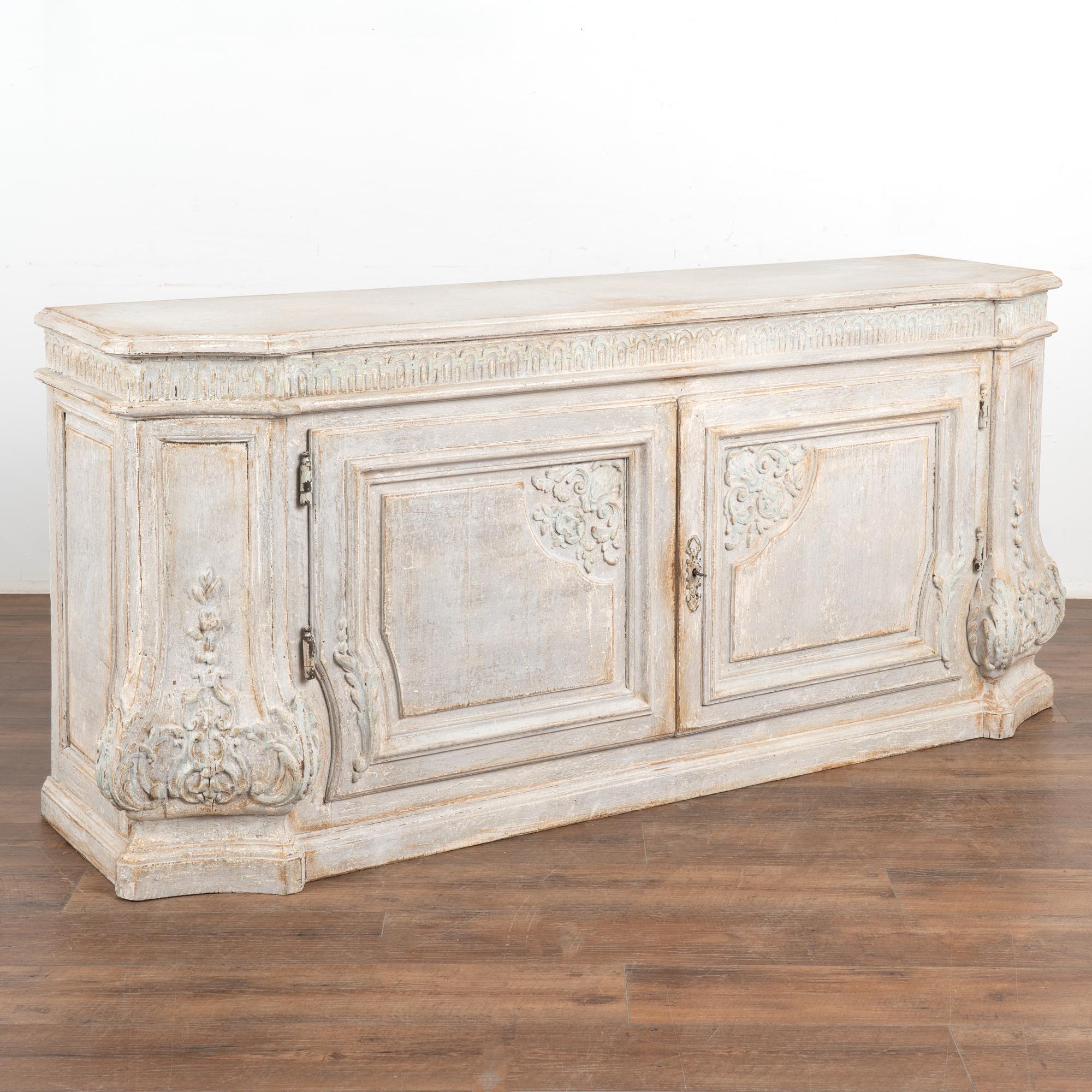 This large Italian oak sideboard has beautifully carved details. At 6' long, this will serve as an impressive buffet or console.
Please enlarge photos to appreciate the newer professionally applied and layered pale blue and soft antique gray which