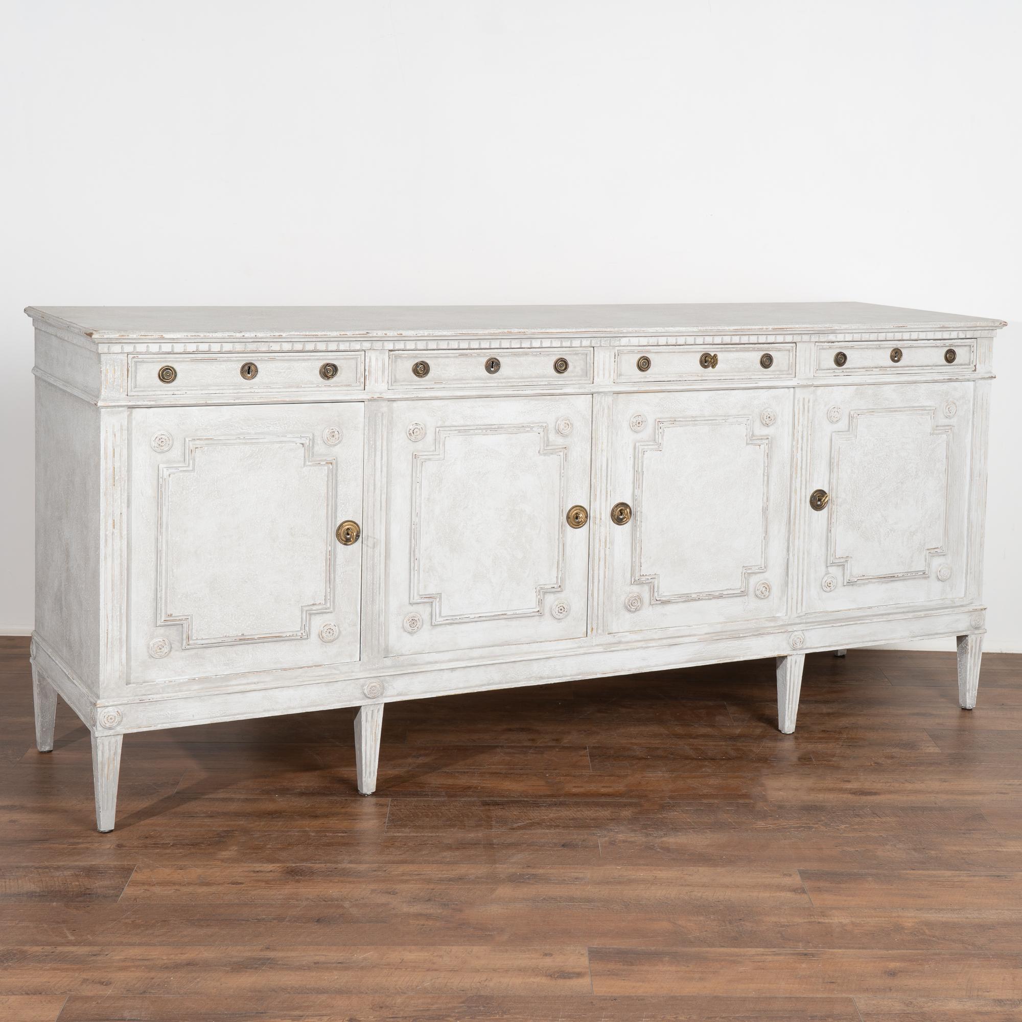 Large pine sideboard with traditional carved panel detail has been given new life with a professionally applied painted layered finish in mottled gray with white undertones.
At over 7' long with four cabinet doors, this will serve as an impressive
