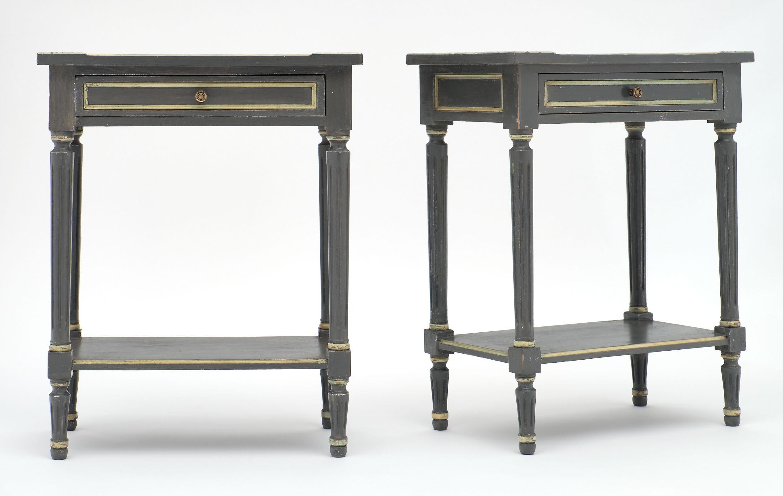 A charming pair of Louis XVI style gray painted side tables made of cherrywood. This pair has been painted in dark gray with light gray painted trim. Each features one dovetailed drawer and original hardware with a shelf below.