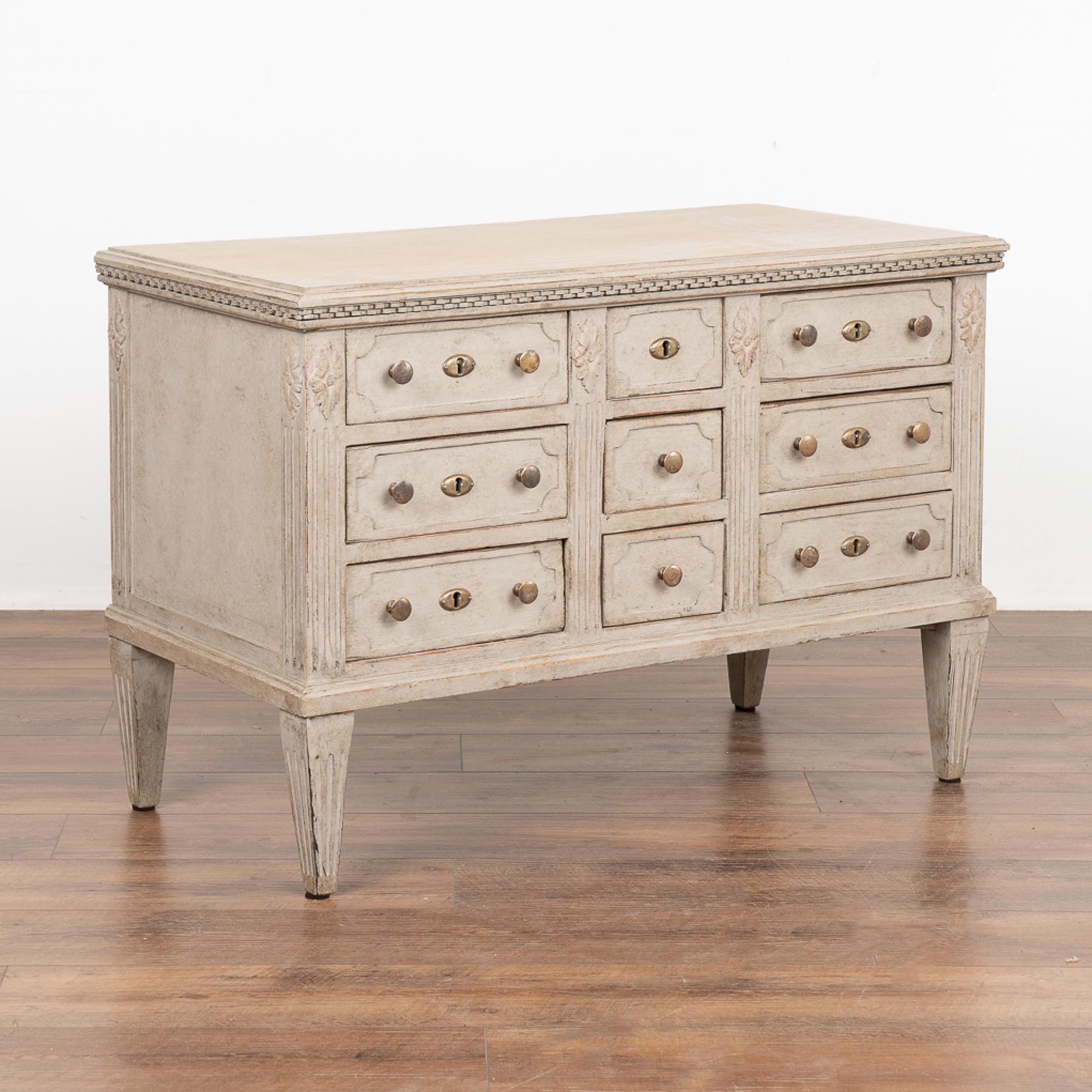 Fascinating Gustavian pine chest of nine drawers with fluted columns, dentil molding and tapered fluted feet.
The unique configuration of drawers with central three in a square shape creates visual intrigue.
The newer, professionally applied layered