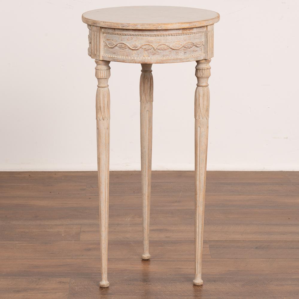 This lovely small round side table stands gracefully on elongated fluted turned legs.
Note the exceptional delicate carved details that add a touch of romance to this petite gustavian table. 
The professionally applied layered gray painted finish
