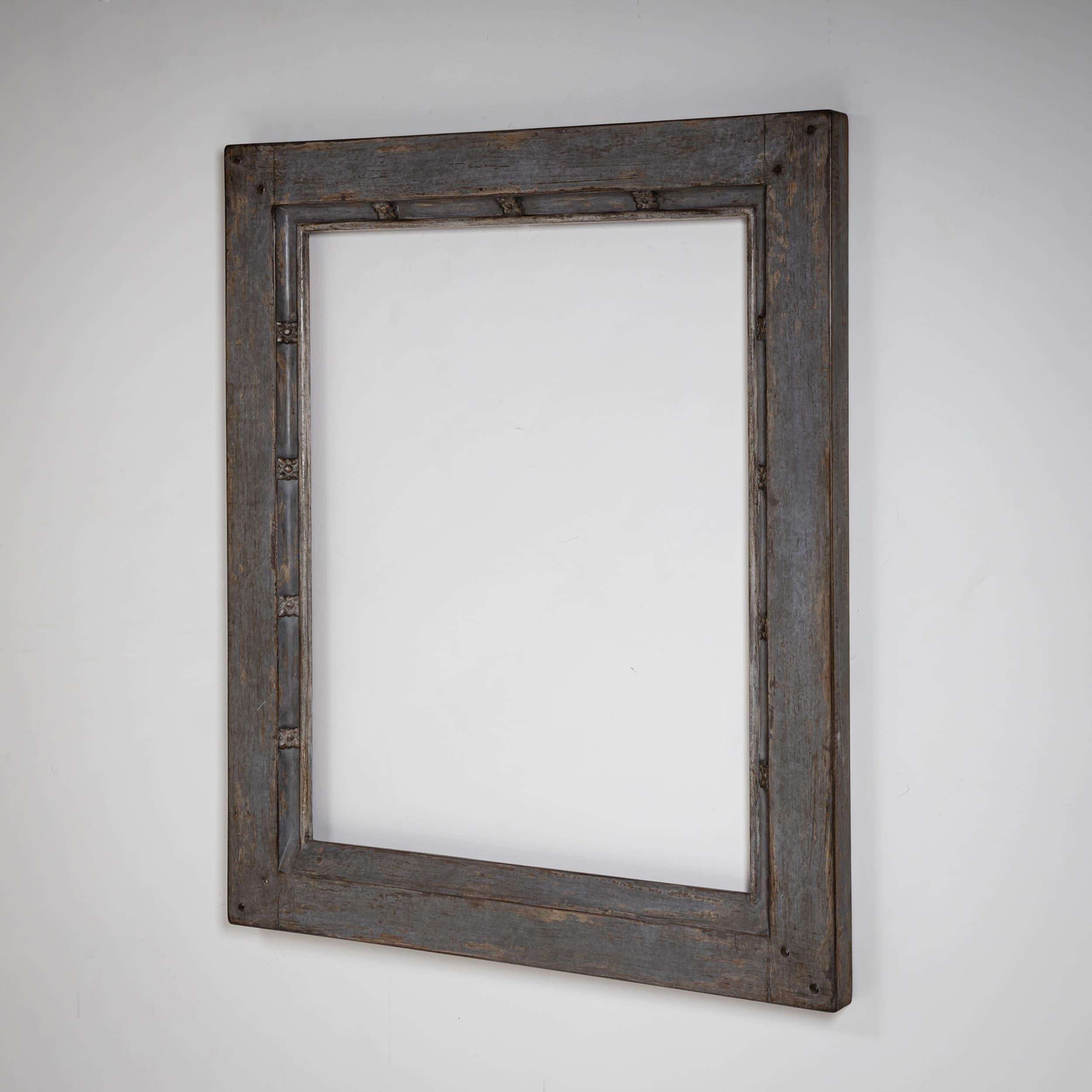 Semplice ma elegante cornice in legno con superficie dipinta di grigio del XIX secolo. Il sottile dettaglio geometrico lungo il bordo interno aggiunge un raffinato tocco decorativo. La patina ne esalta il carattere storico.