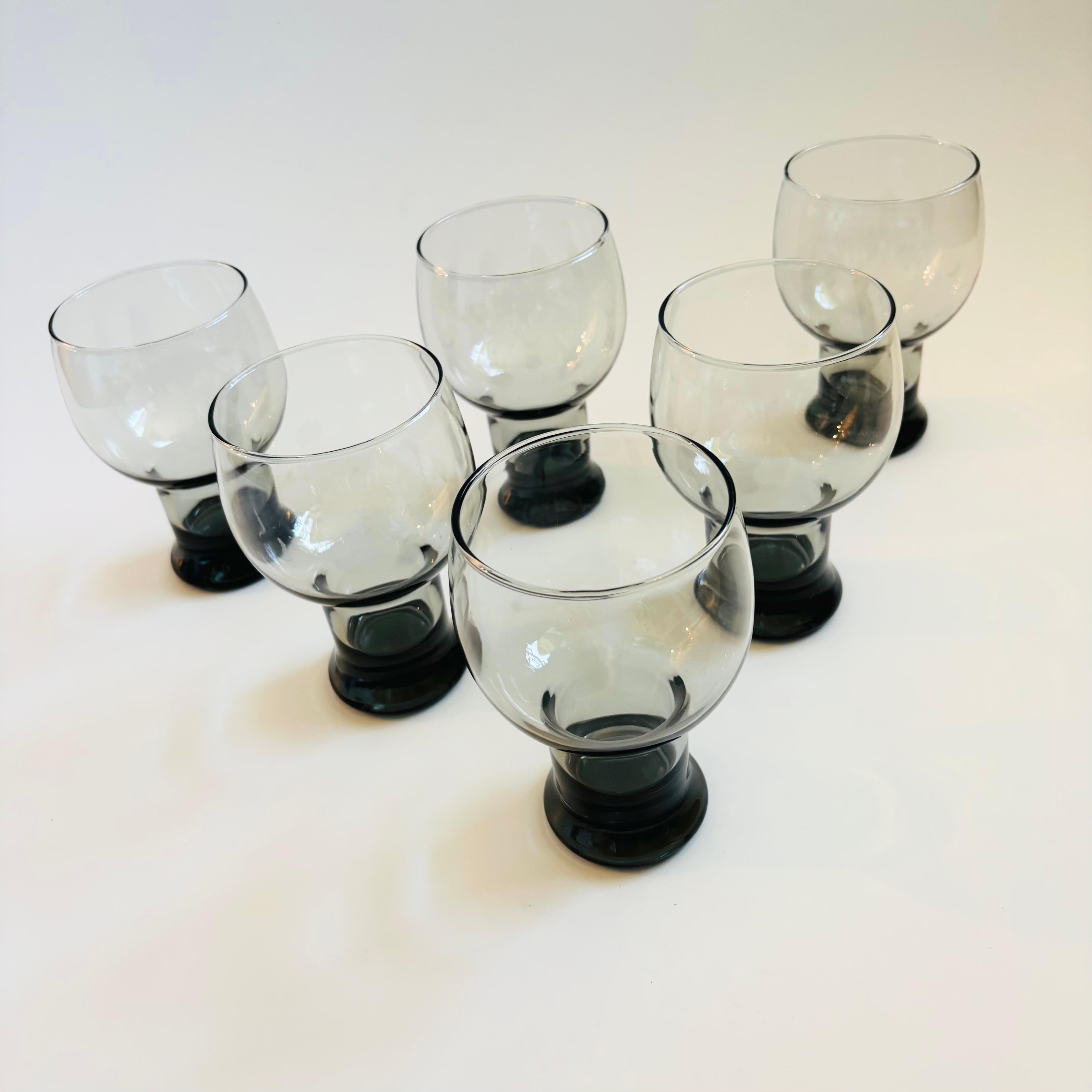 A set of 6 glasses in moody dark gray glass. Nice dramatic shapes with round tops and pedestal bases. Perfect for cocktails or as water glasses.

